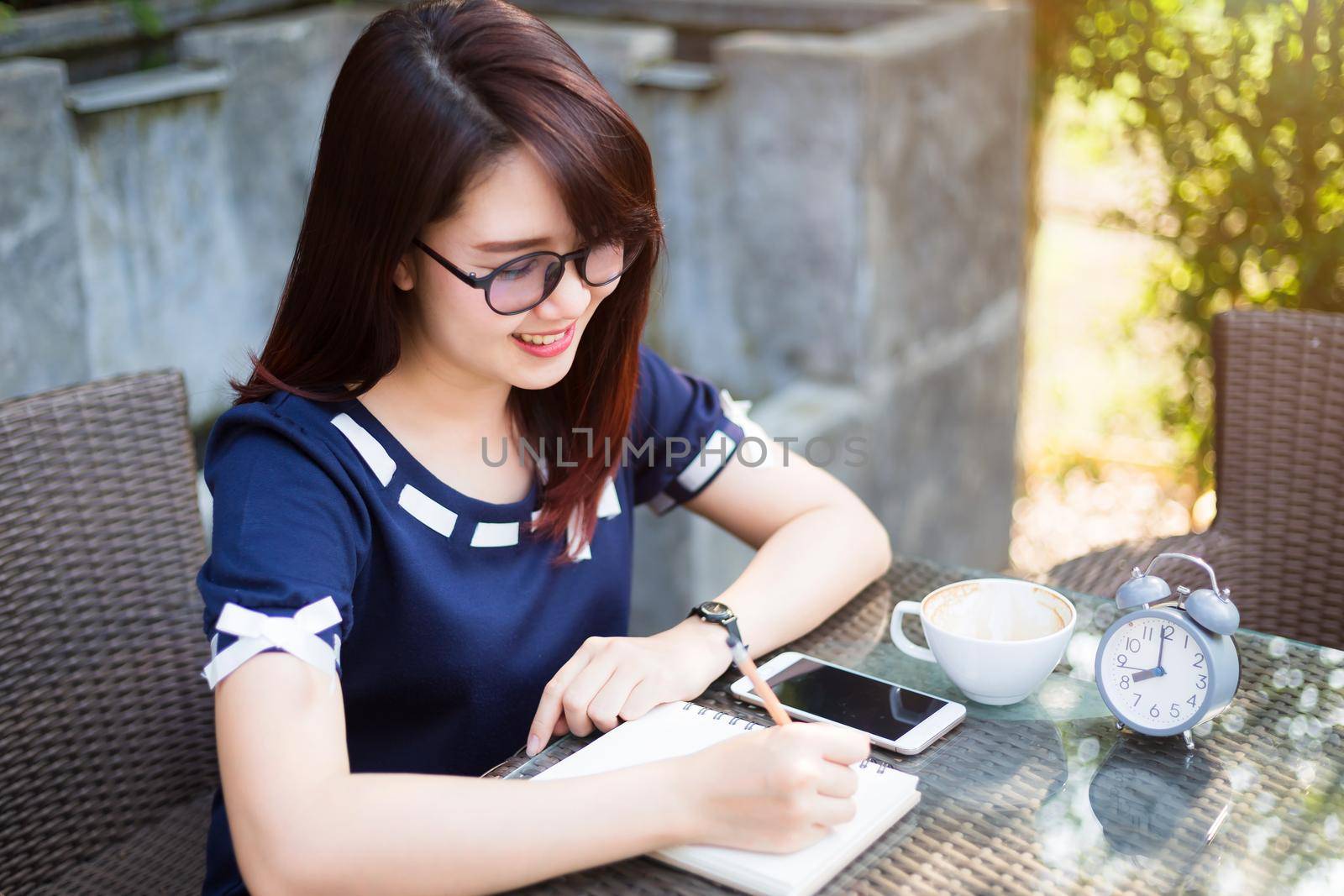 Asian young business woman between the thinking working make a note of something making and clock in summer park or office outdoor.