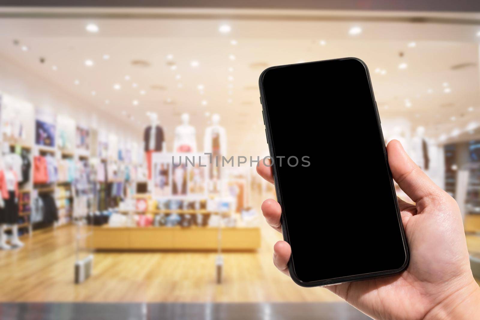 Close-up of female use smartphone blurred images in the mall and Clothes shop blur of the background. by tinapob2534