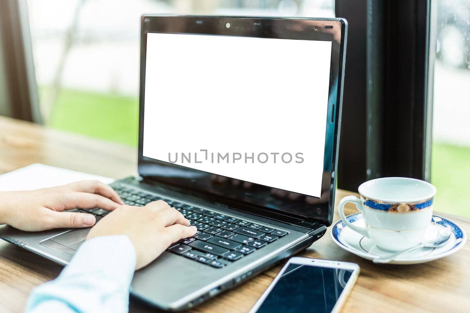 Close-up of Business woman working with smartphone,laptop with blank white screen and document in coffee shop like the background.