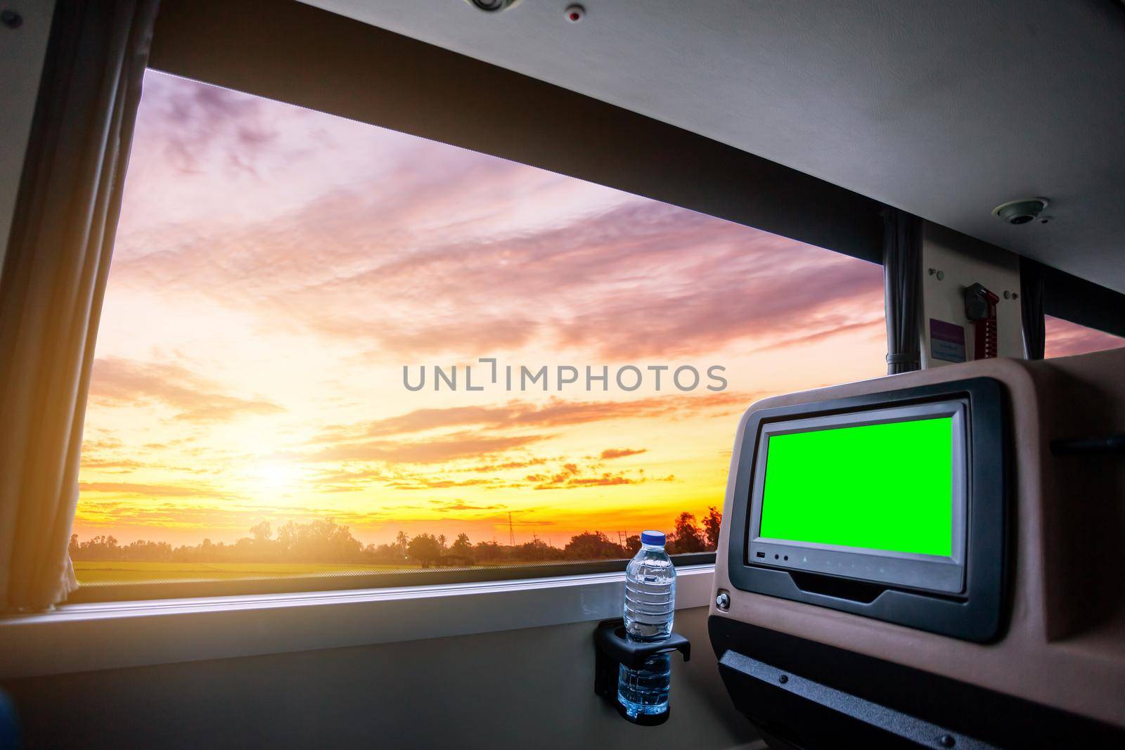 Inside of the bus which has LCD screen blank rear seat for entertainment with a bottle of water and window view of Beautiful landscape nature with sky cloud sunset, Figure tourism road trip concept.