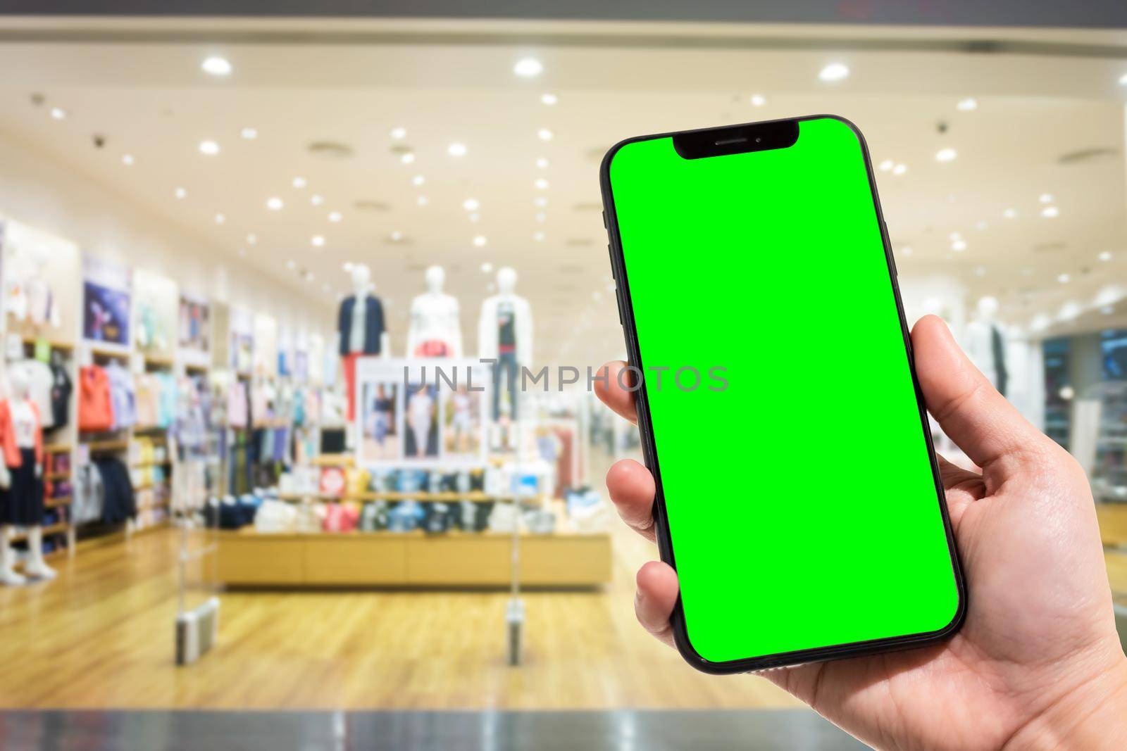 Close-up of female use smartphone blurred images in the mall and Clothes shop blur of the background.