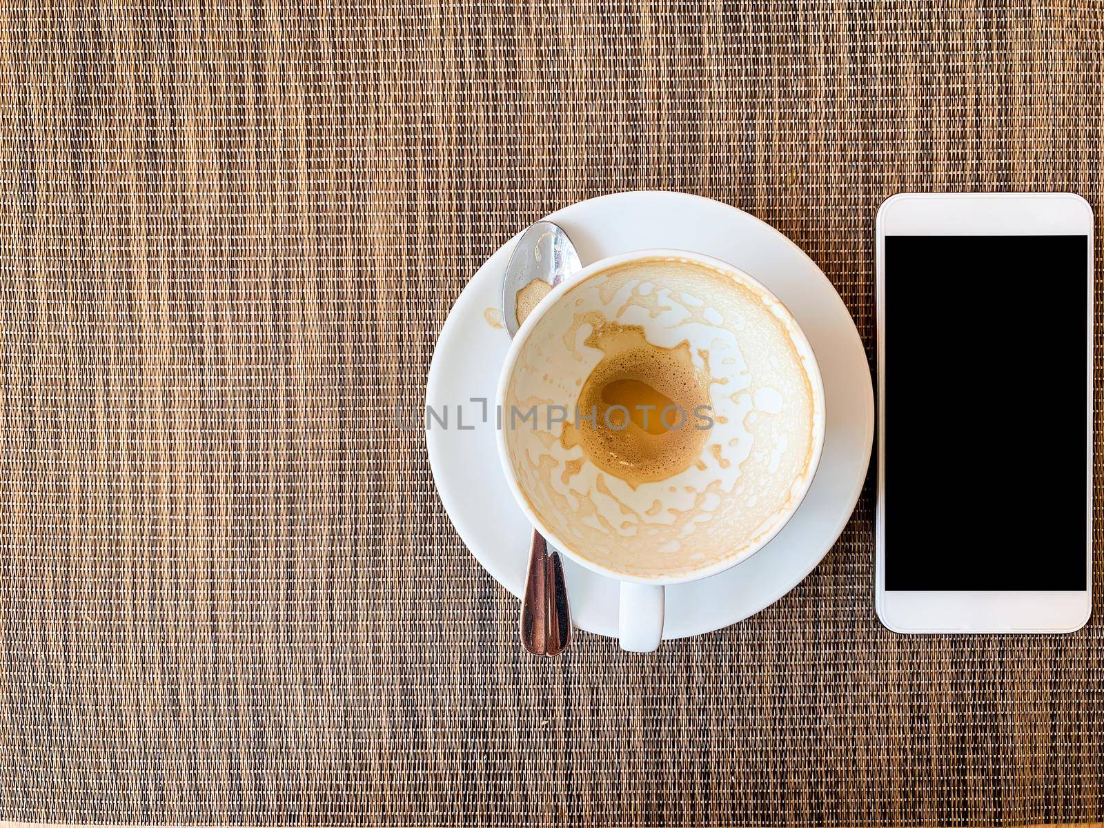 Smartphone and Empty coffee cup on wood desk on top view.  by tinapob2534