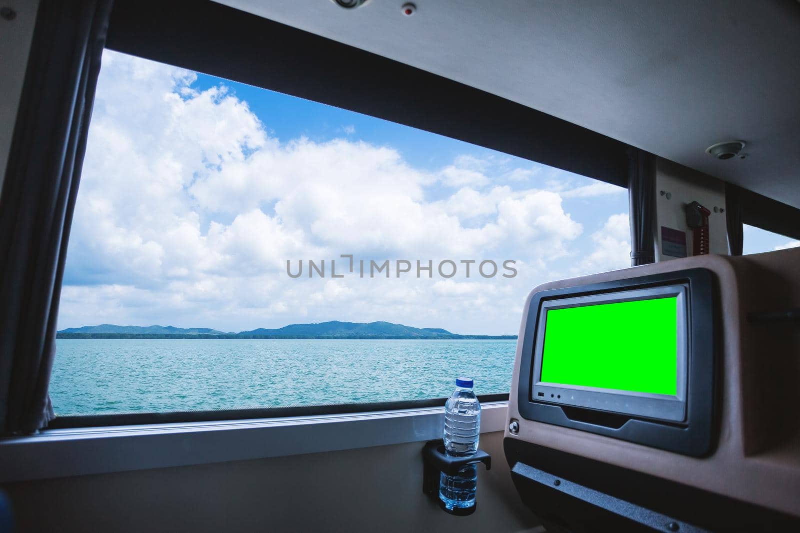 Inside of the bus which has LCD screen blank rear seat for entertainment with a bottle of water and window view of Beautiful landscape nature the sea with sky cloud, Figure tourism road trip concept.