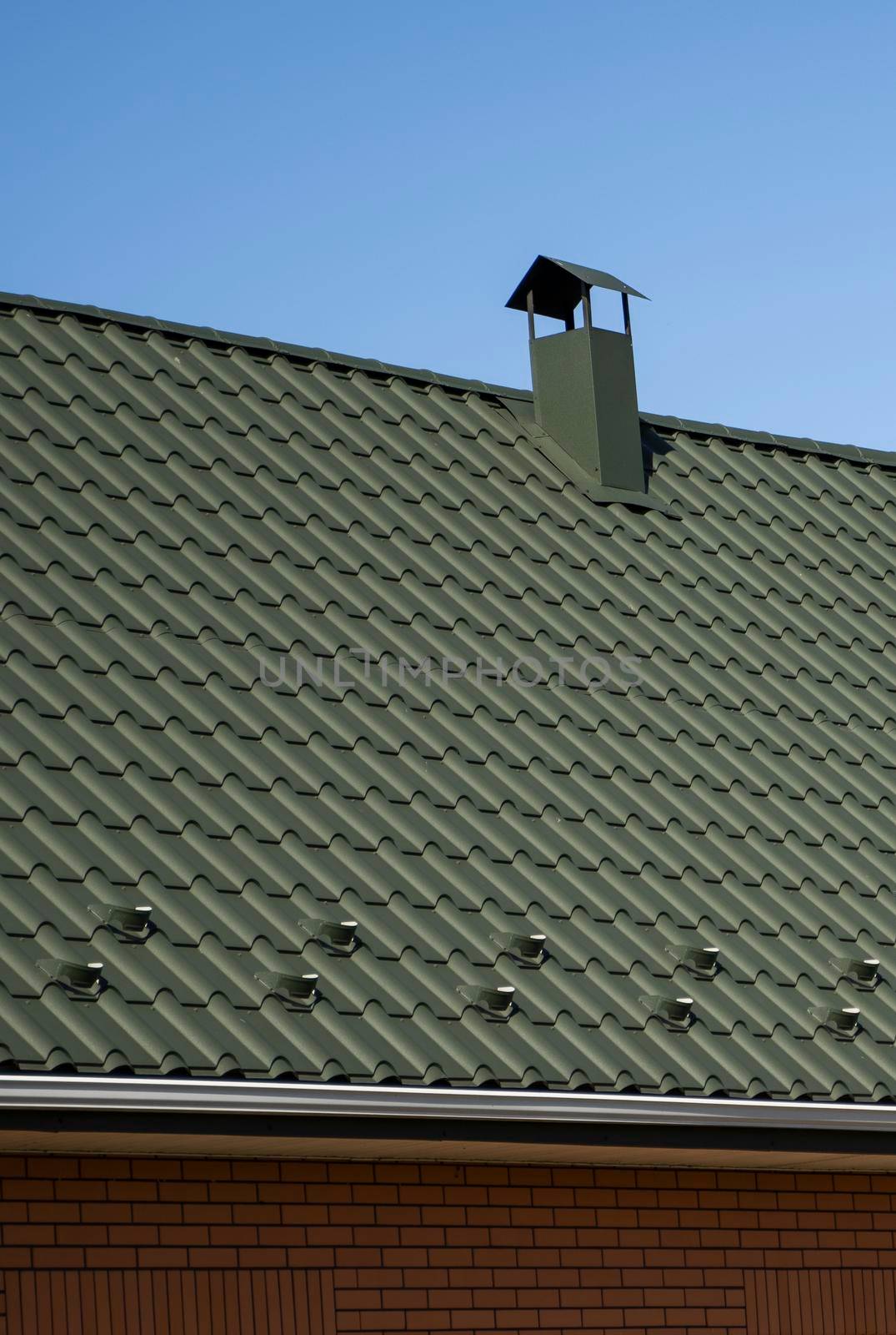 Green corrugated metal profile roof installed on a modern house. The roof of corrugated sheet. Roofing of metal profile wavy shape. Modern roof made of metal. Metal roofing