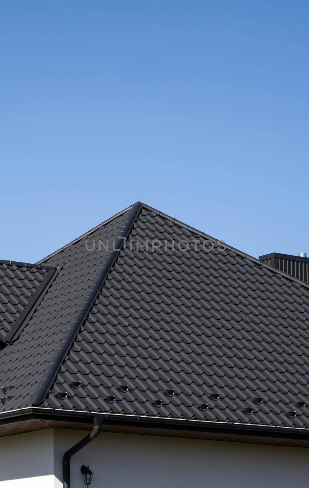 Brown corrugated metal profile roof installed on a modern house. The roof of corrugated sheet. Roofing of metal profile wavy shape. Modern roof made of metal. Metal roofing