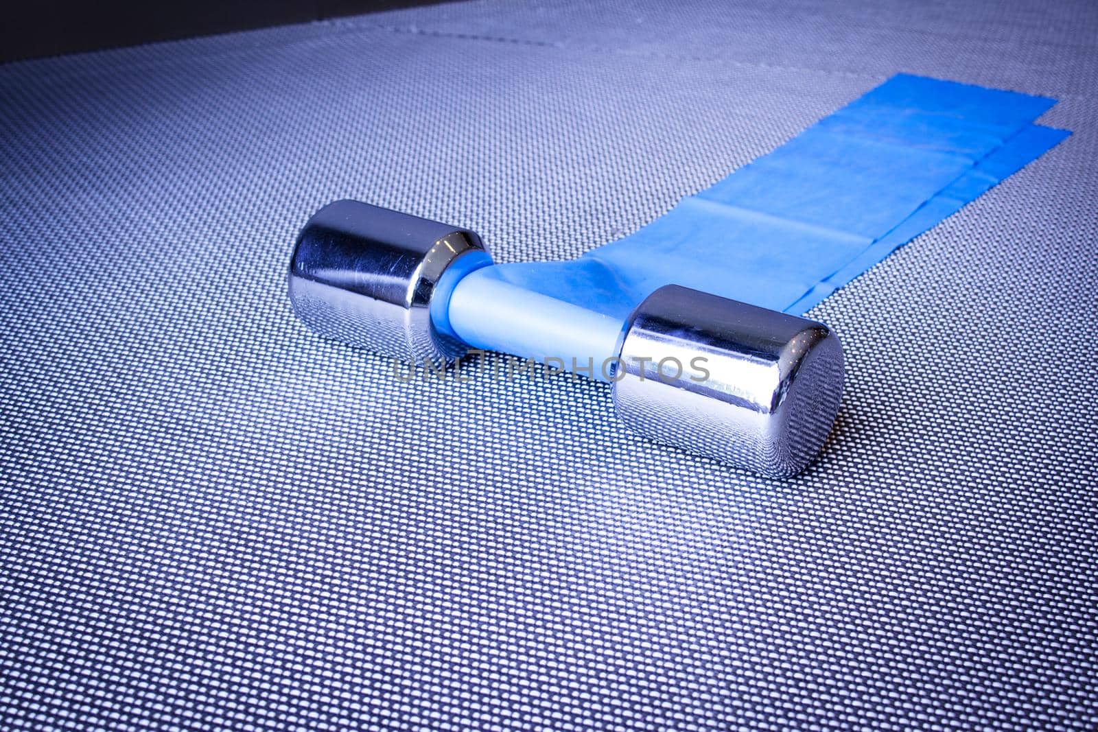 Silver dumbbell next to elastic band for pilates exercises. No people