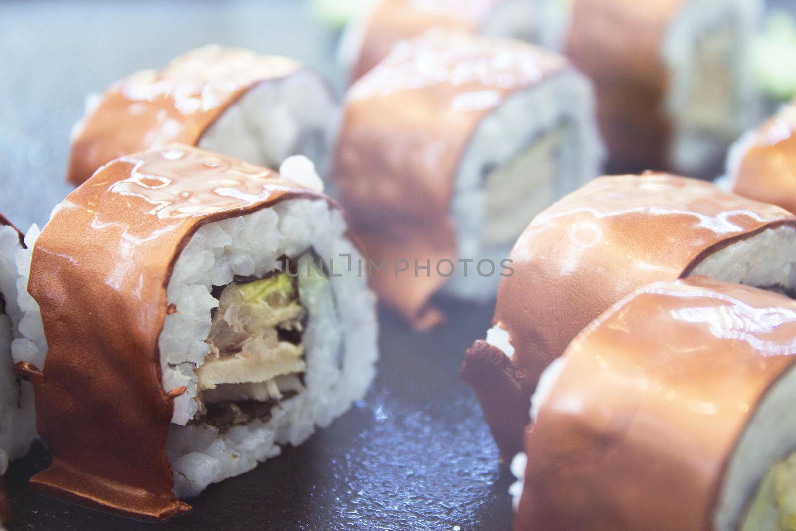 Assorted sushi food on a black slate plate. No people