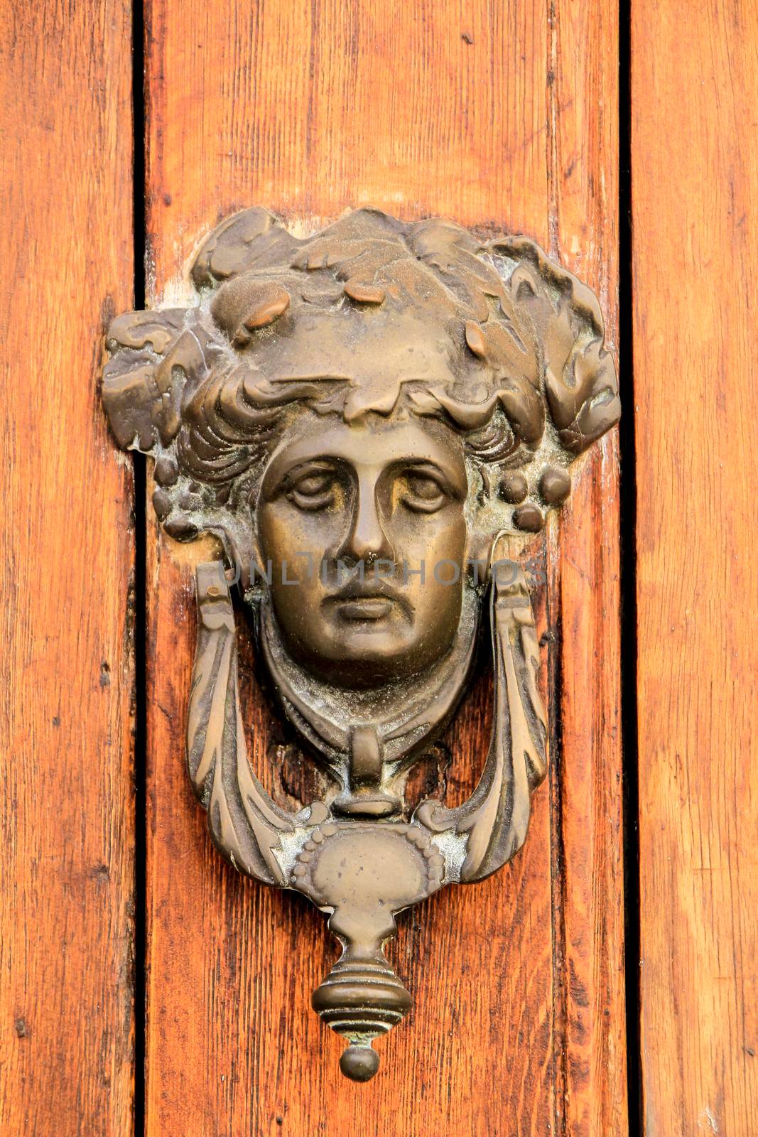 Vintage door knocker face shape on brown wooden door in Altea, Alicante, Spain