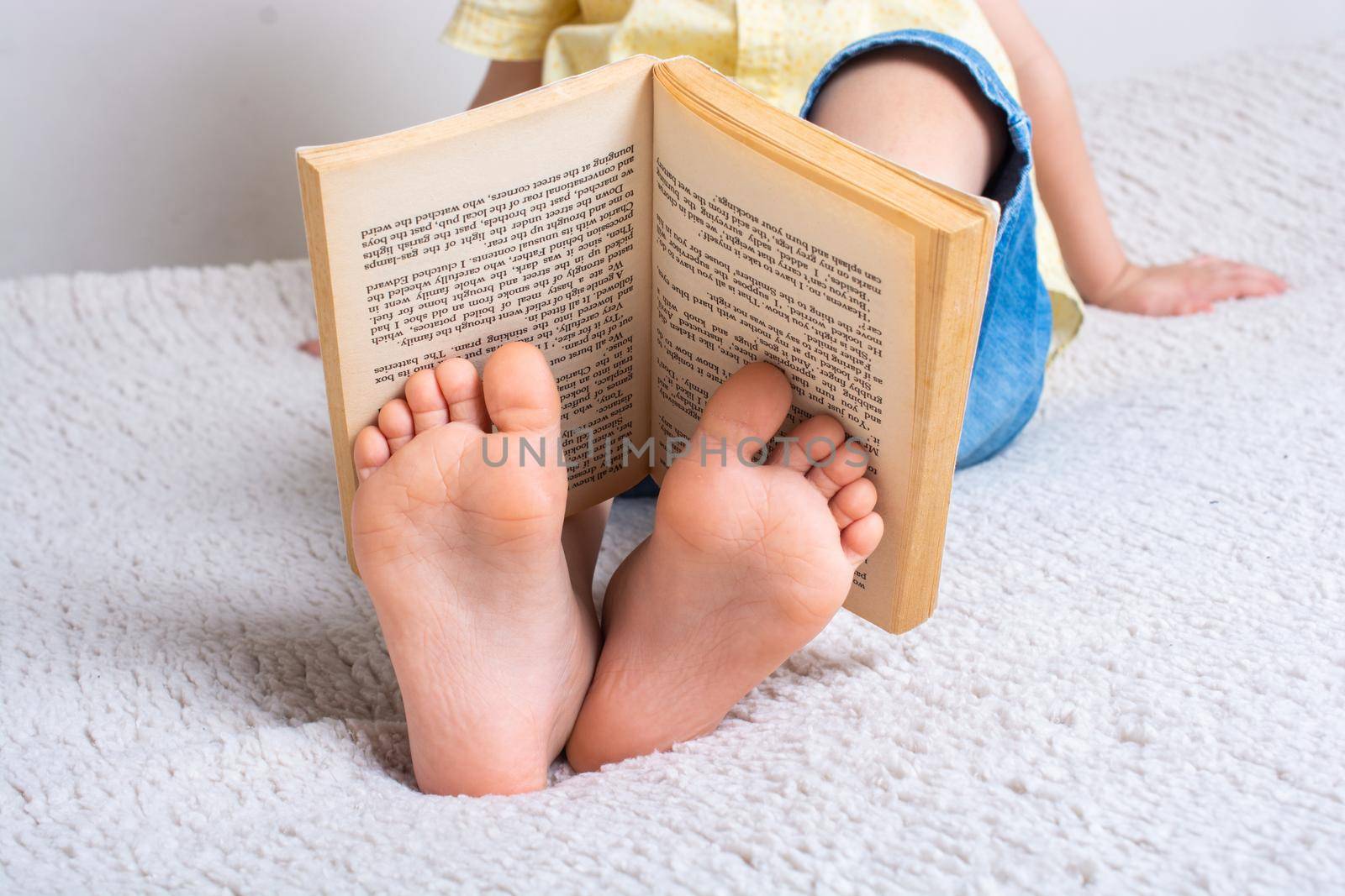Boy with book on feet  as education concept