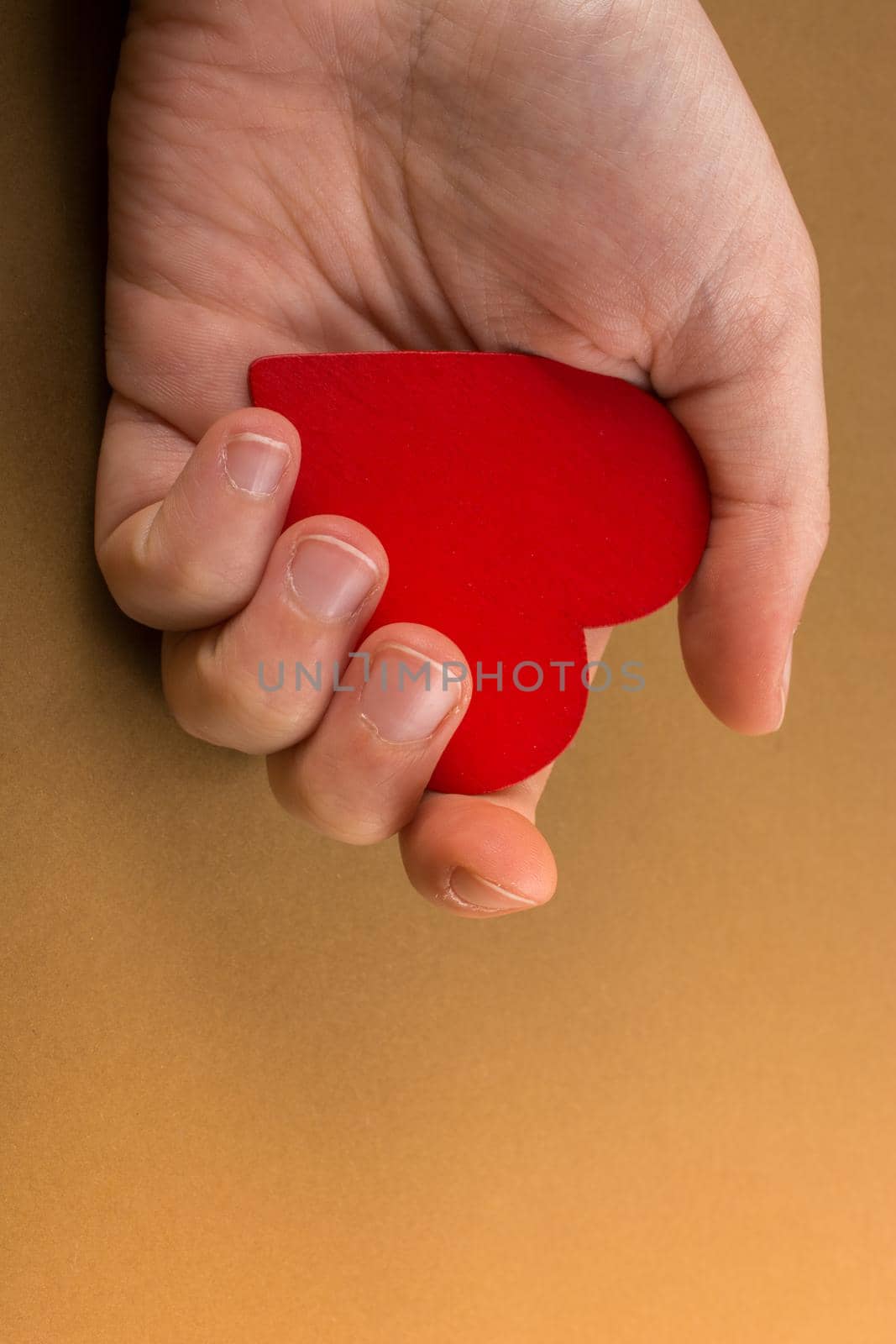 Red color heart shaped object in hand  on dotted paper