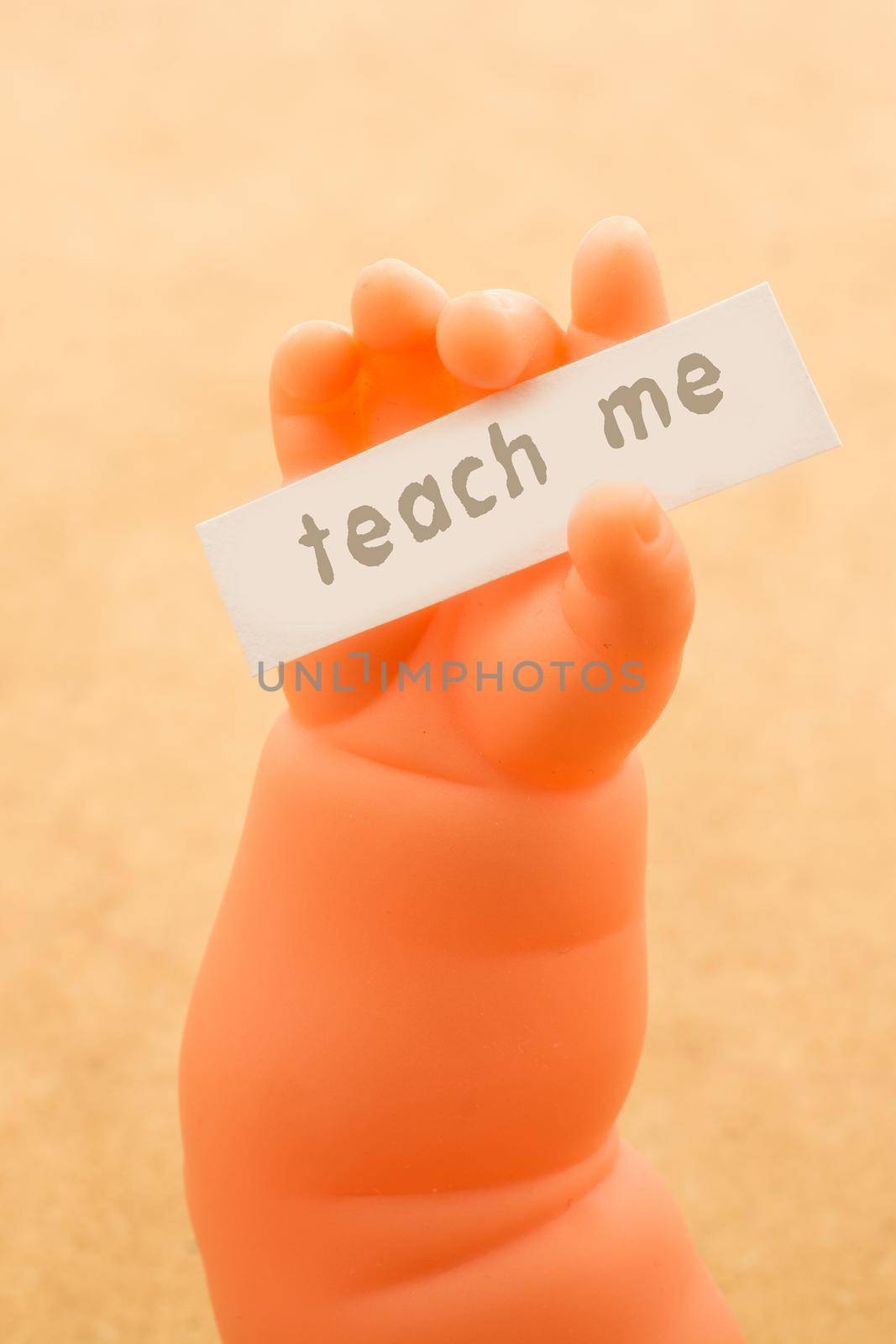 Toy doll hand holding paper with TEACH ME wording