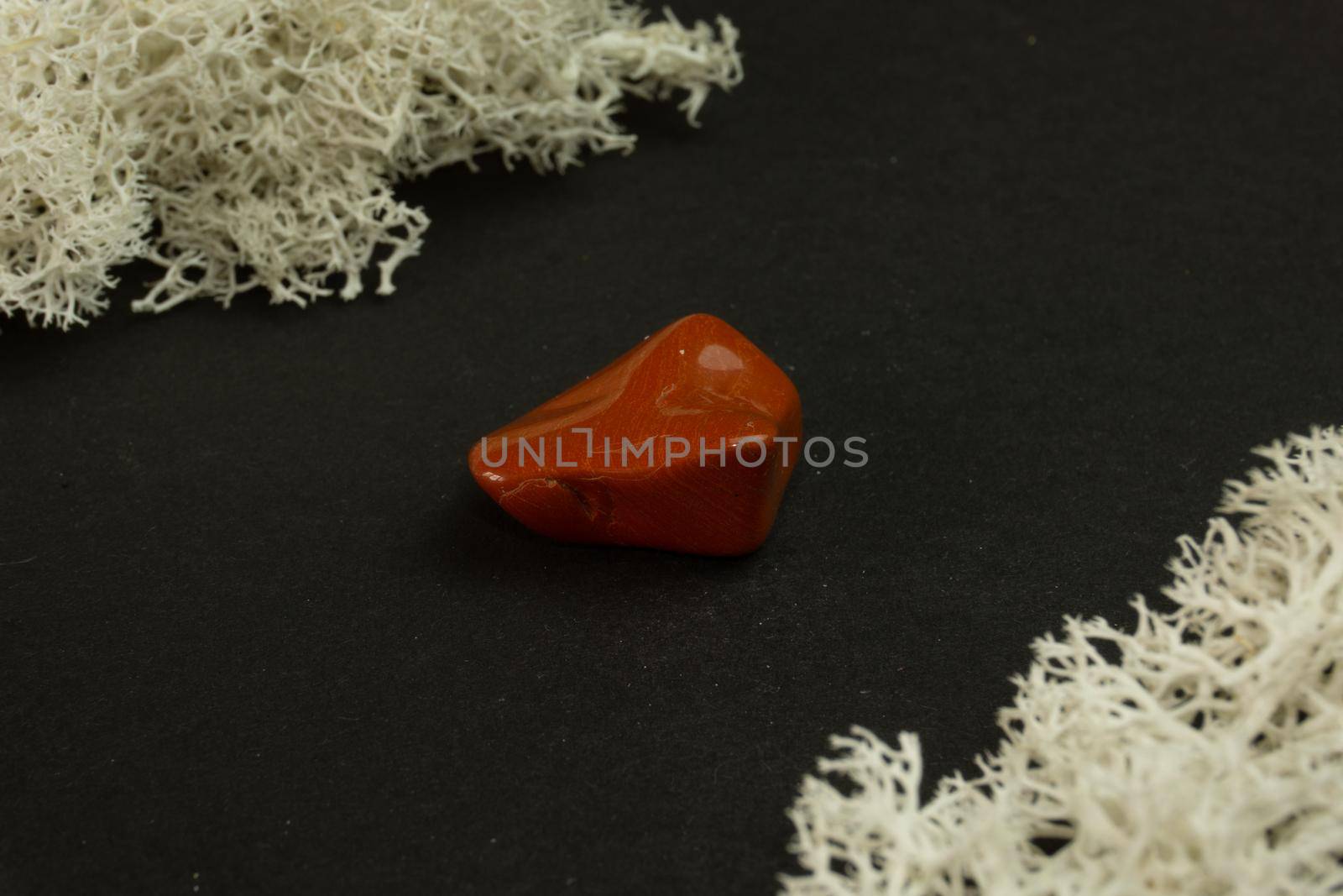 Red Jasper from Brazil. Natural mineral stone on black background. Mineralogy, geology, magic of stones, semi-precious stones and samples of minerals. Close-up macro photo