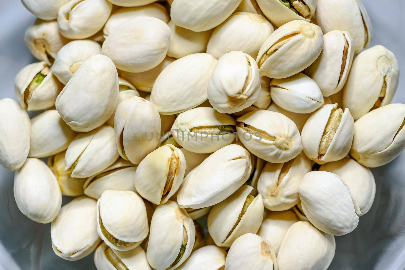 Close-up top view a pile of beans it has a white nut shell dry and hard of Pistachio, Pistache or Pistacia vera in a bowl food delicious salty snack