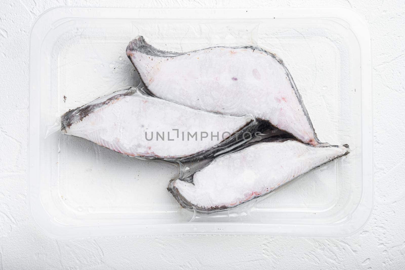 Frozen Greenland halibut steaks vacuum pack set, on white stone table background, top view flat lay