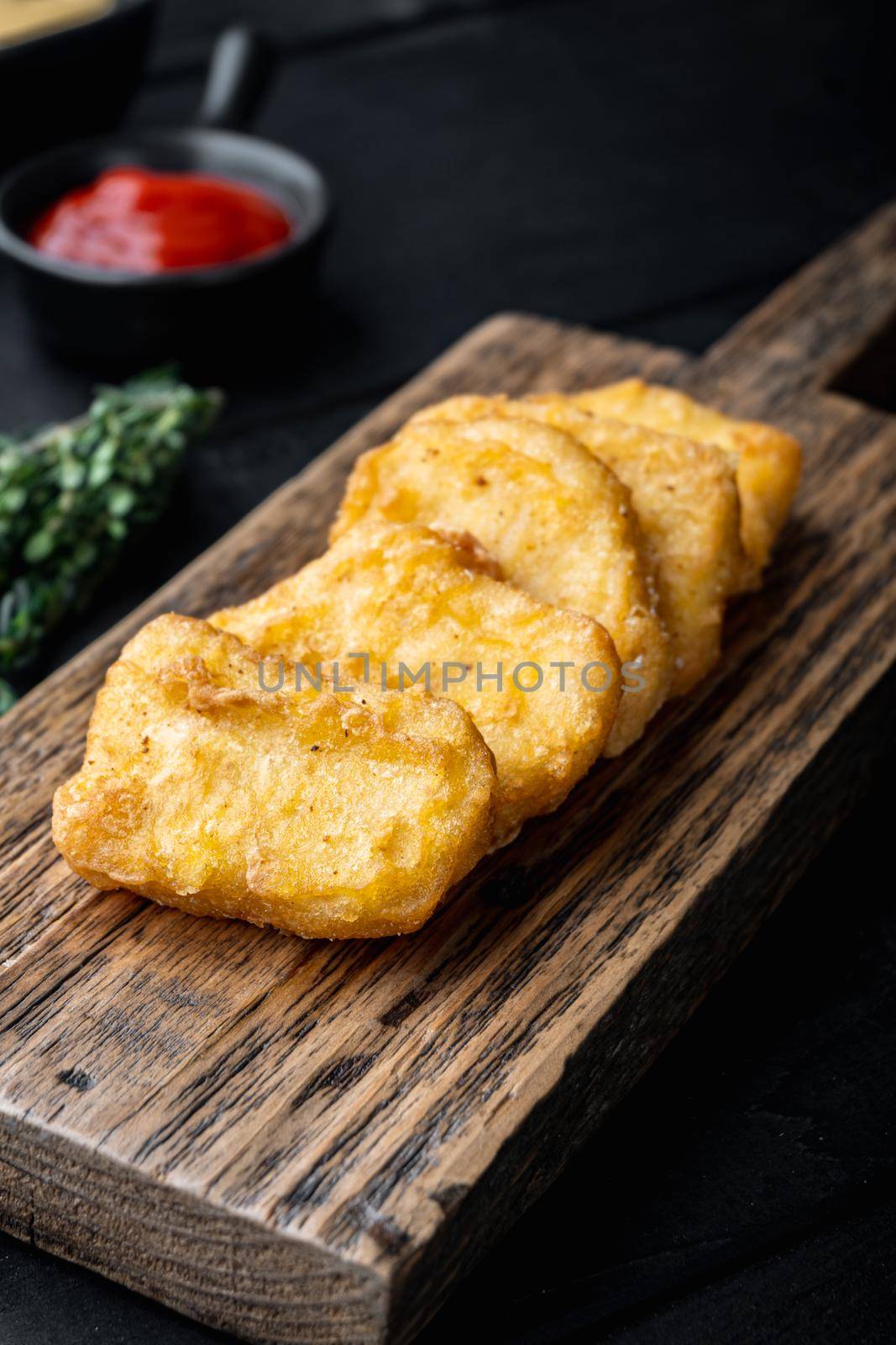 Homemade chicken nuggets fried on black wooden table.