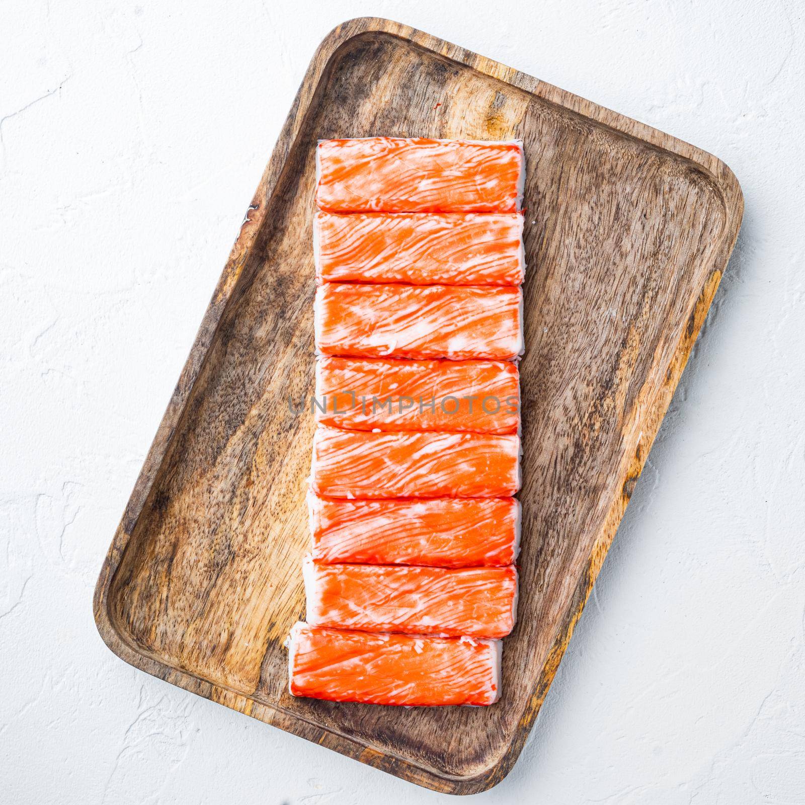 Fresh Crab meat stick surimi with blue swimming crab, on wooden tray, on white background, top view flat lay by Ilianesolenyi