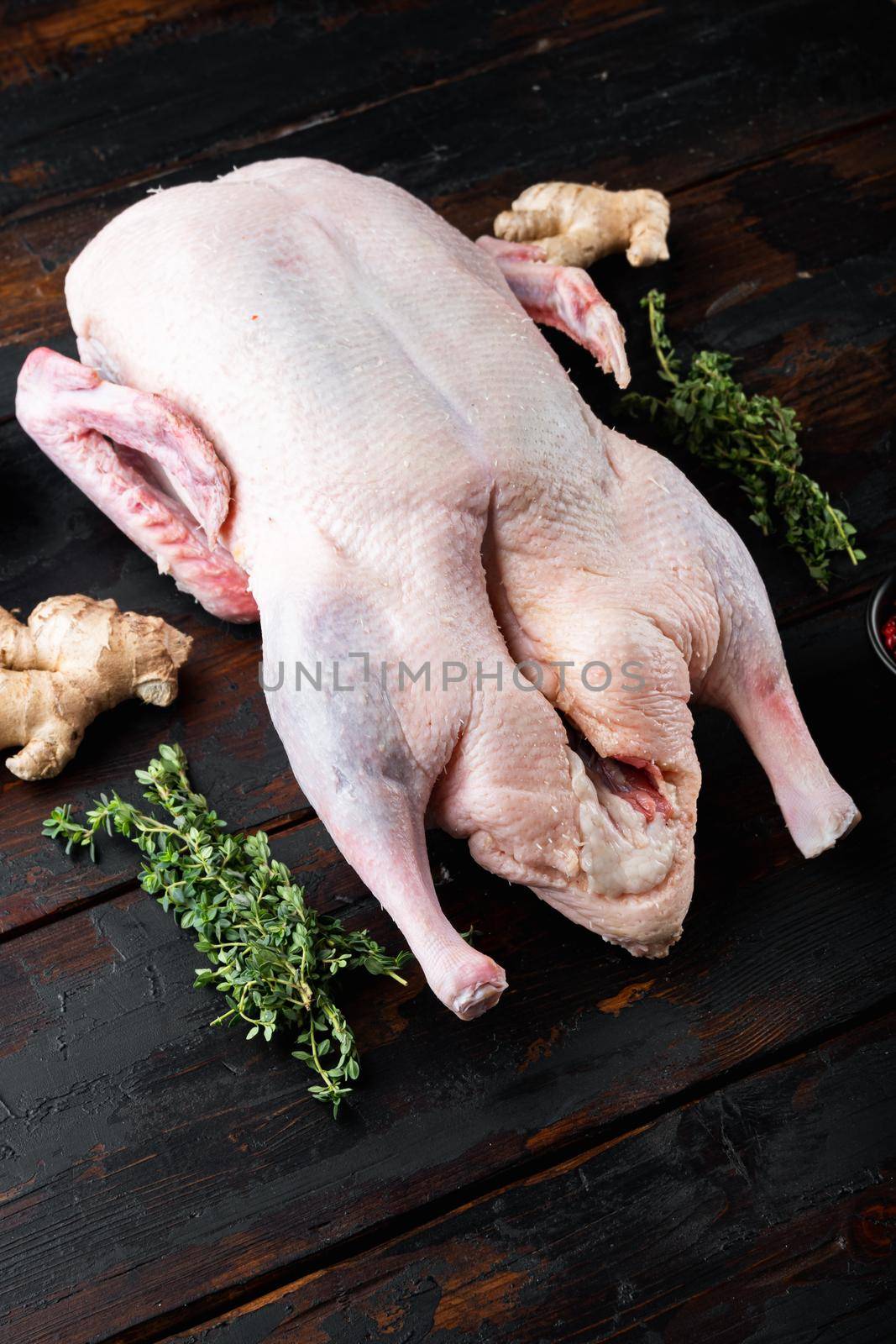 Raw whole mallard duck meat on dark wooden background.