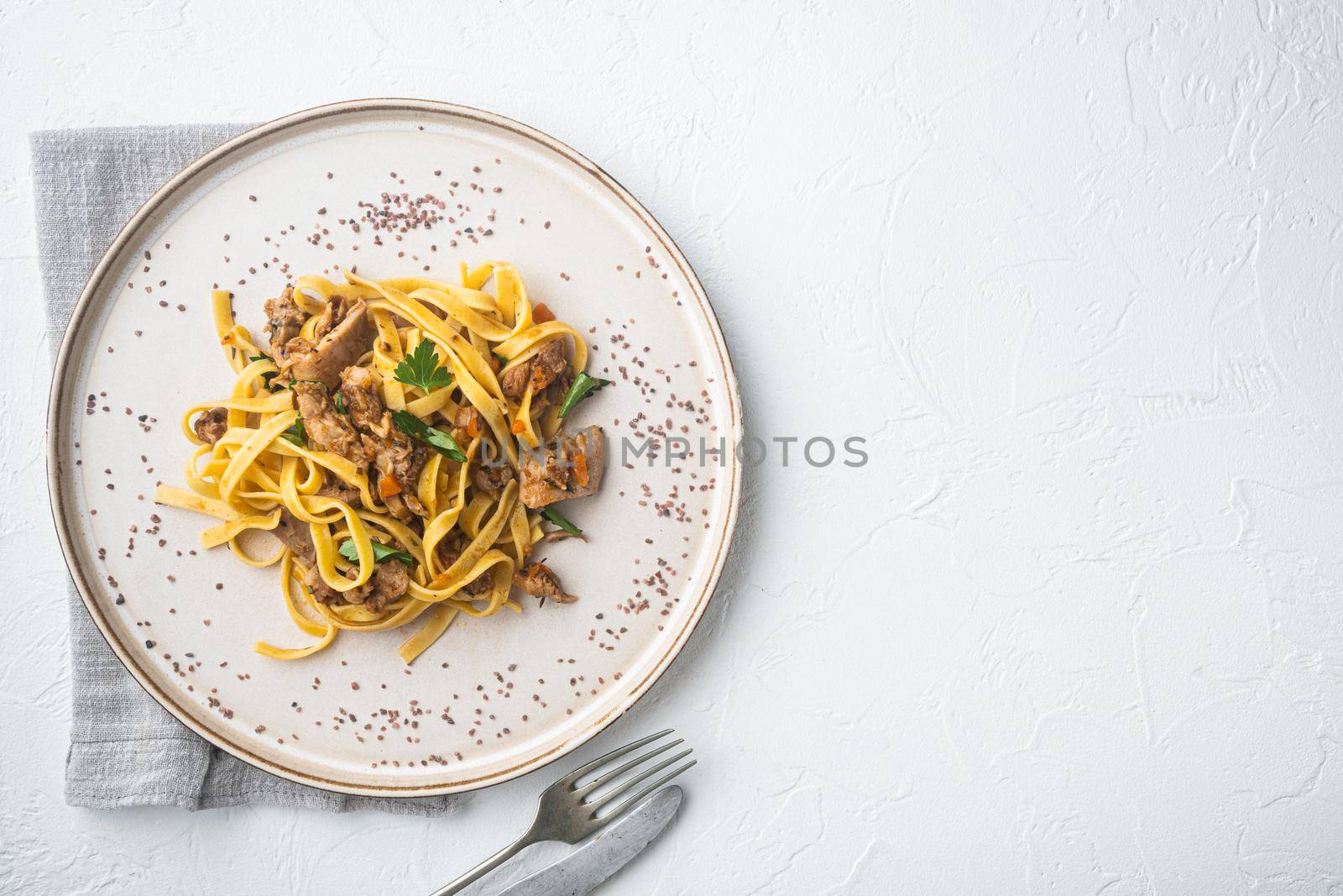 Rabbit stew tagliatelle set, on plate, on white stone background, top view flat lay, with copy space for text