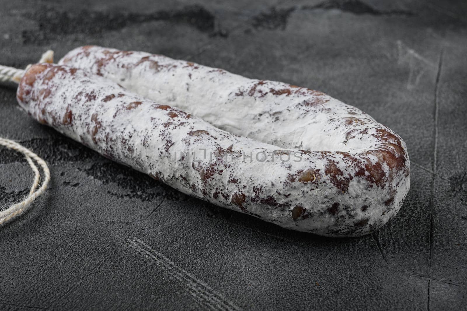 Dry salami sausage fuet on grey textured background.