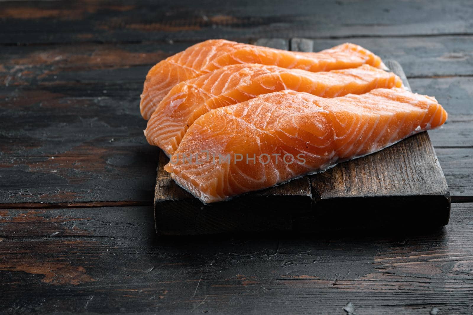 Fresh raw salmon fillet cuts, on old wooden table with space for text