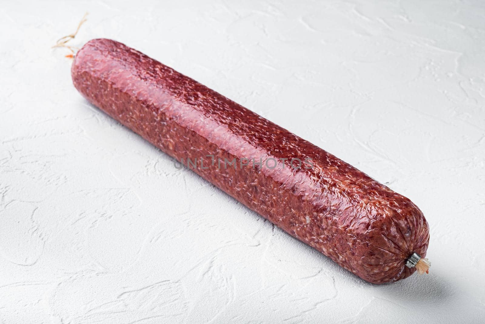 Whole sausage salami set, on white stone background, with copy space for text