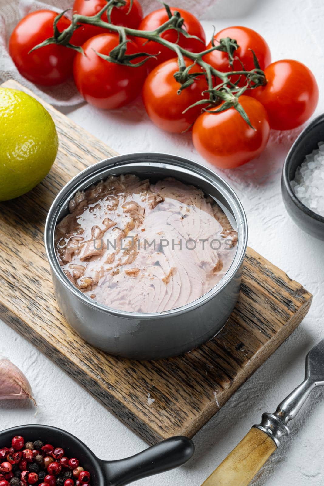 Canned Wild Yellowfin Tuna set, on wooden cutting board, on white background with herbs and ingredients