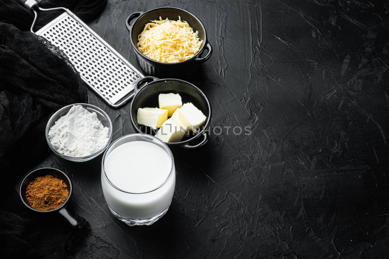 Preparation of bechamel cheese white sauce set, on black stone background, with copy space for text