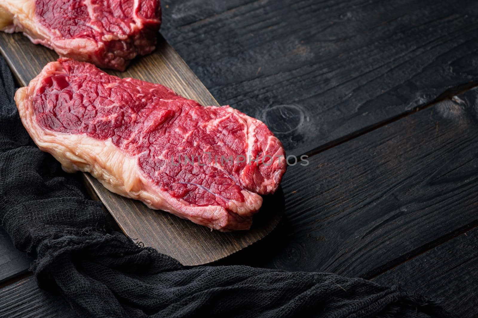 Top loin, fresh organic beef meat cut, on black wooden table, with copy space for text