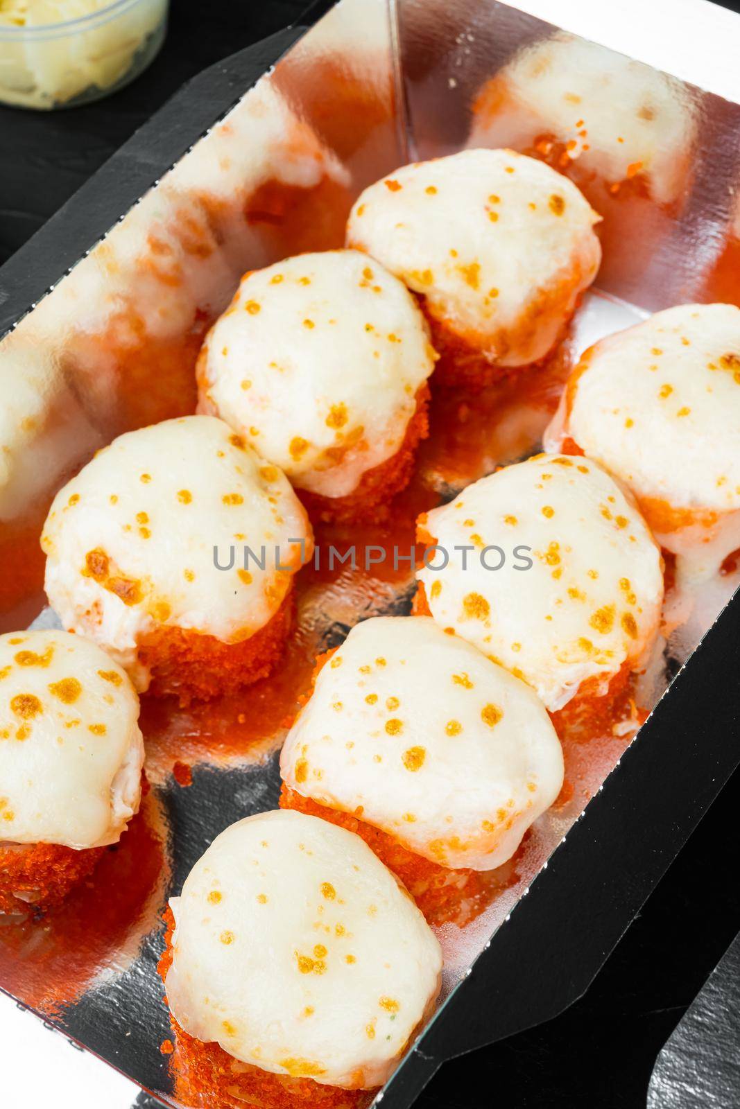 Set of sushi rolls in delivery food box set, on black stone background