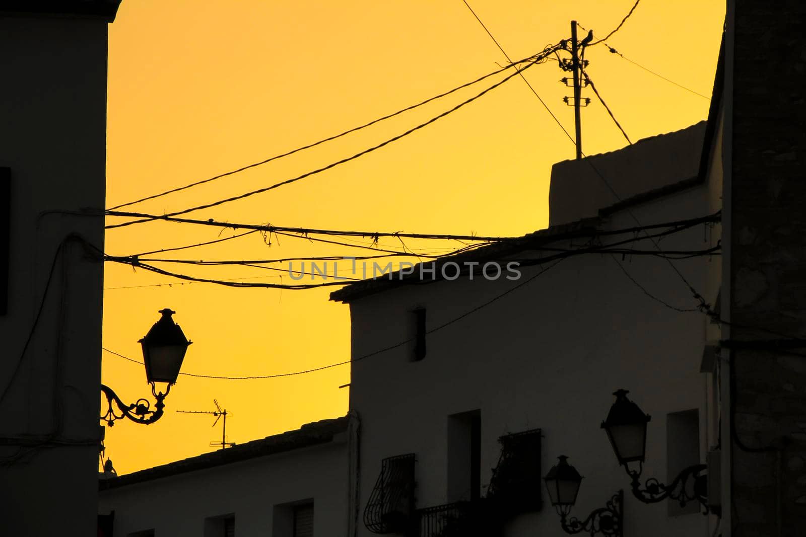 Orange sunset with houses and streetlight silhouettes in Altea, Alicante, Spain in summer