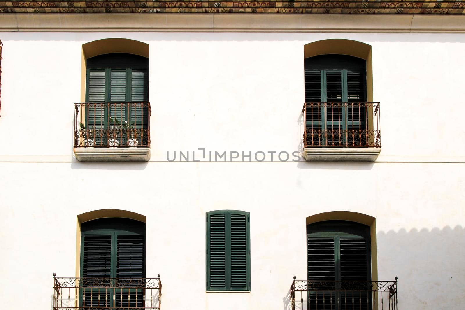 Whitewashed facade with window with forged metal grill and vintage streetlight in Altea village, Alicante, Spain
