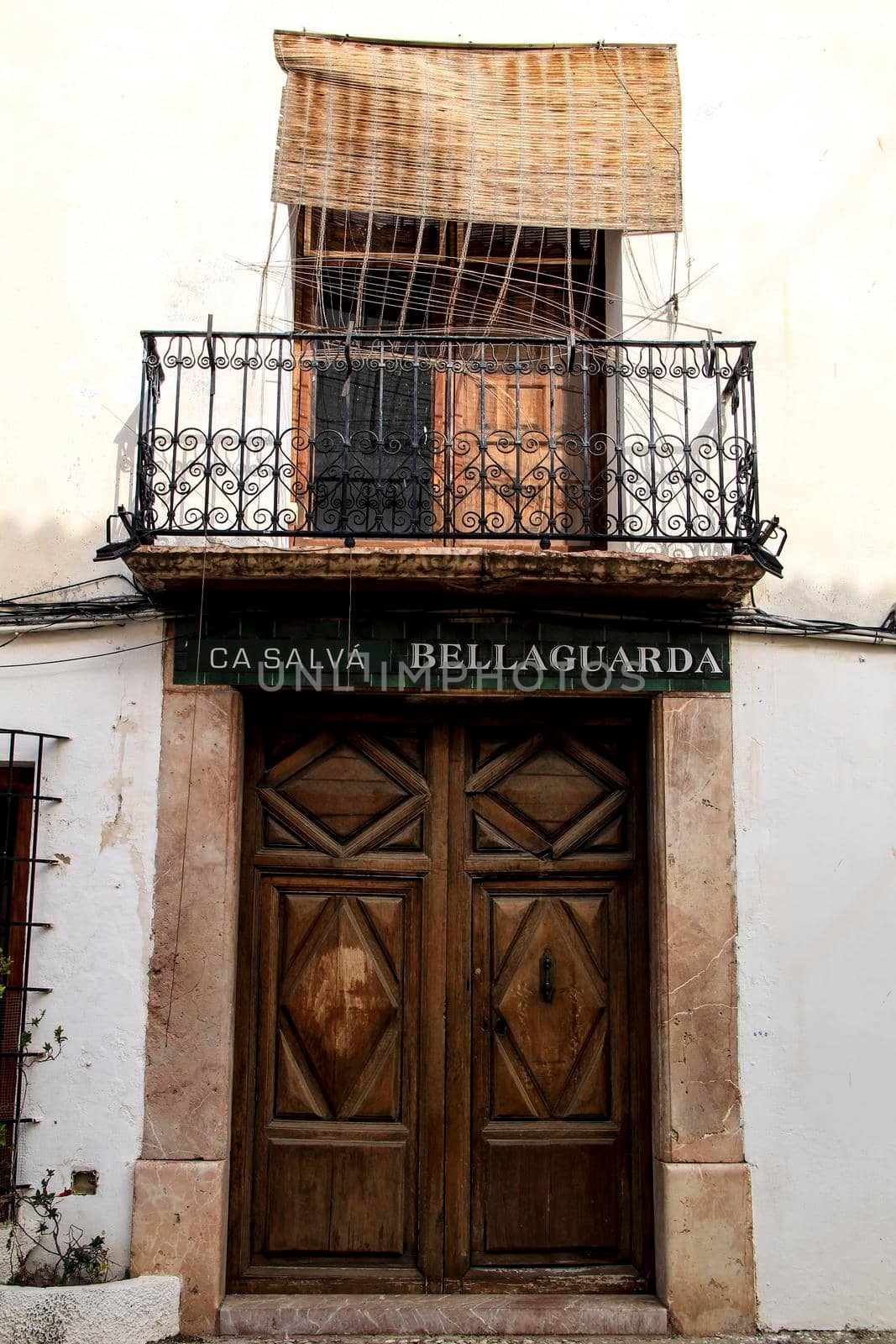 Altea, Alicante, Spain- June 1, 2021:Facade with wooden door and balcony with forged metal grill in Altea village, Alicante, Spain