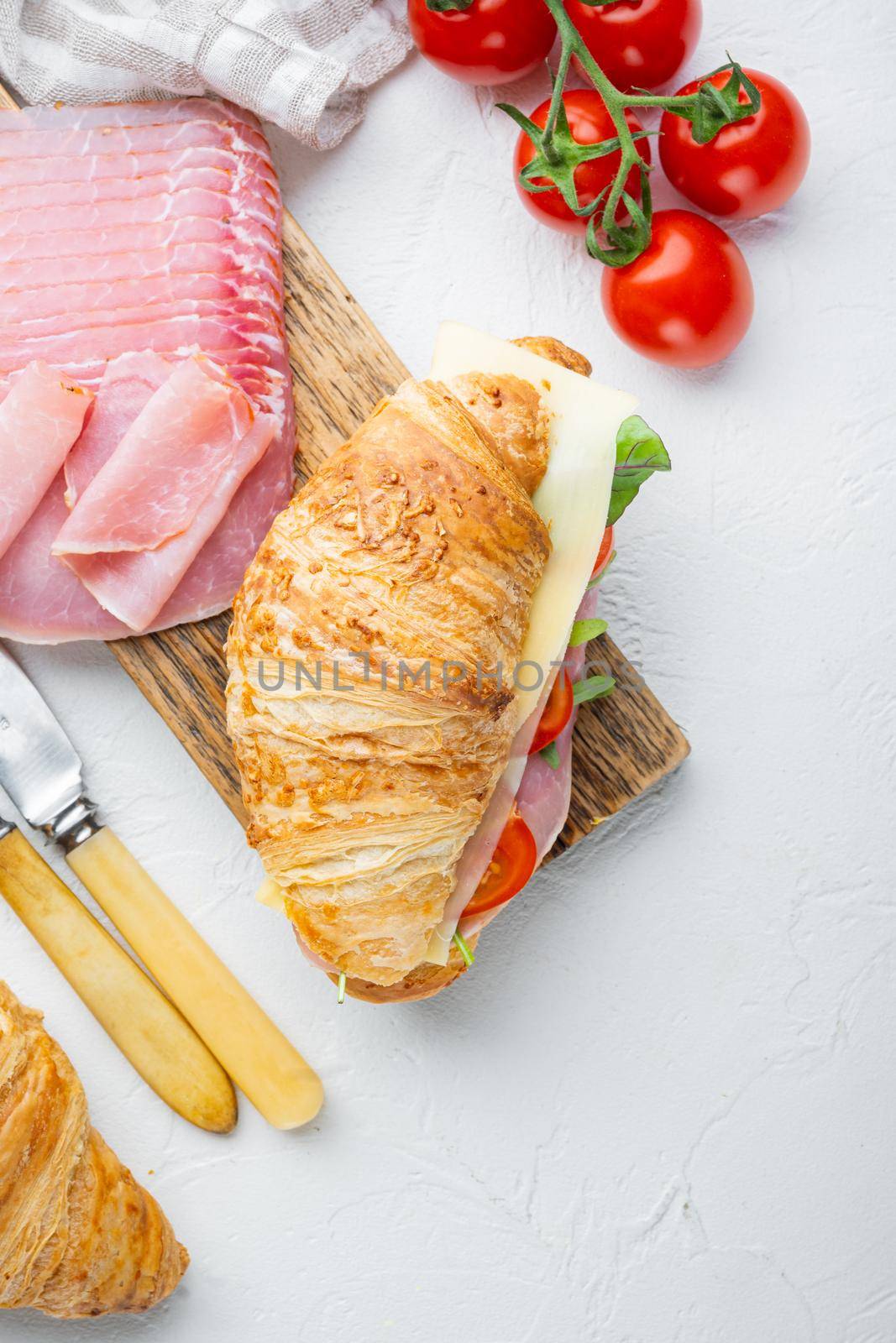 French food for breakfast. Baked Croissant sandwich with ham greens and cheese set, with herbs and ingredients, on white stone background, top view flat lay, with copy space for text