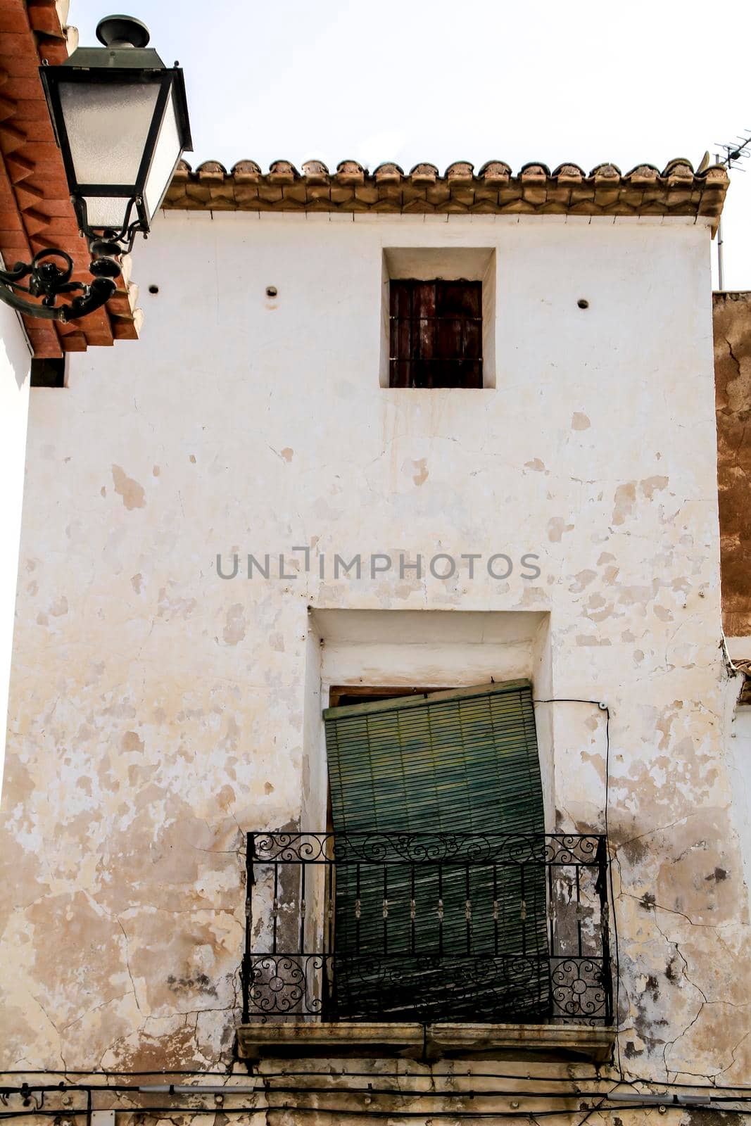 Old house facade with rusty balcony and green blind in Altea, Alicante, Spain