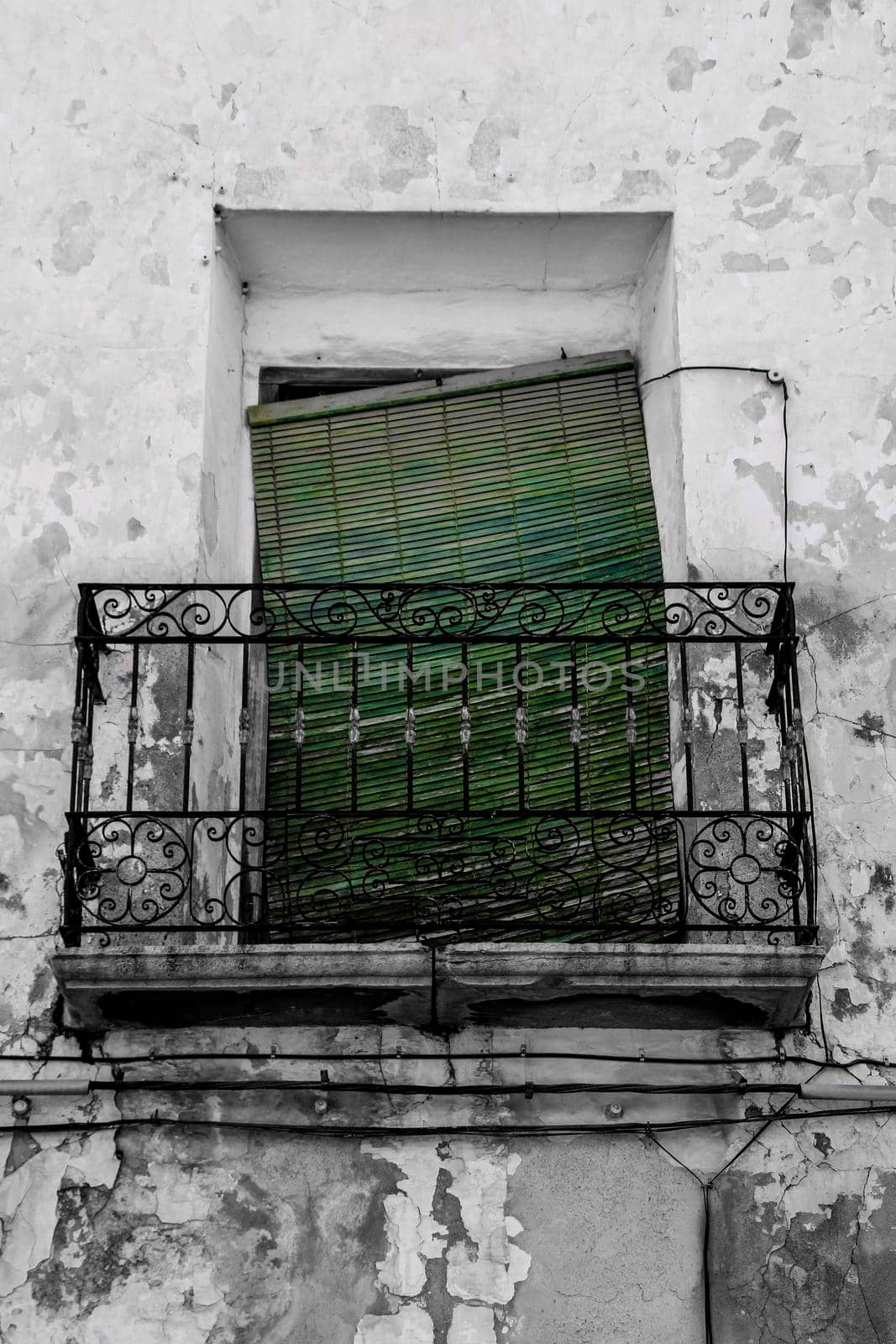 Old house facade with rusty balcony and green blind in Altea, Alicante, Spain