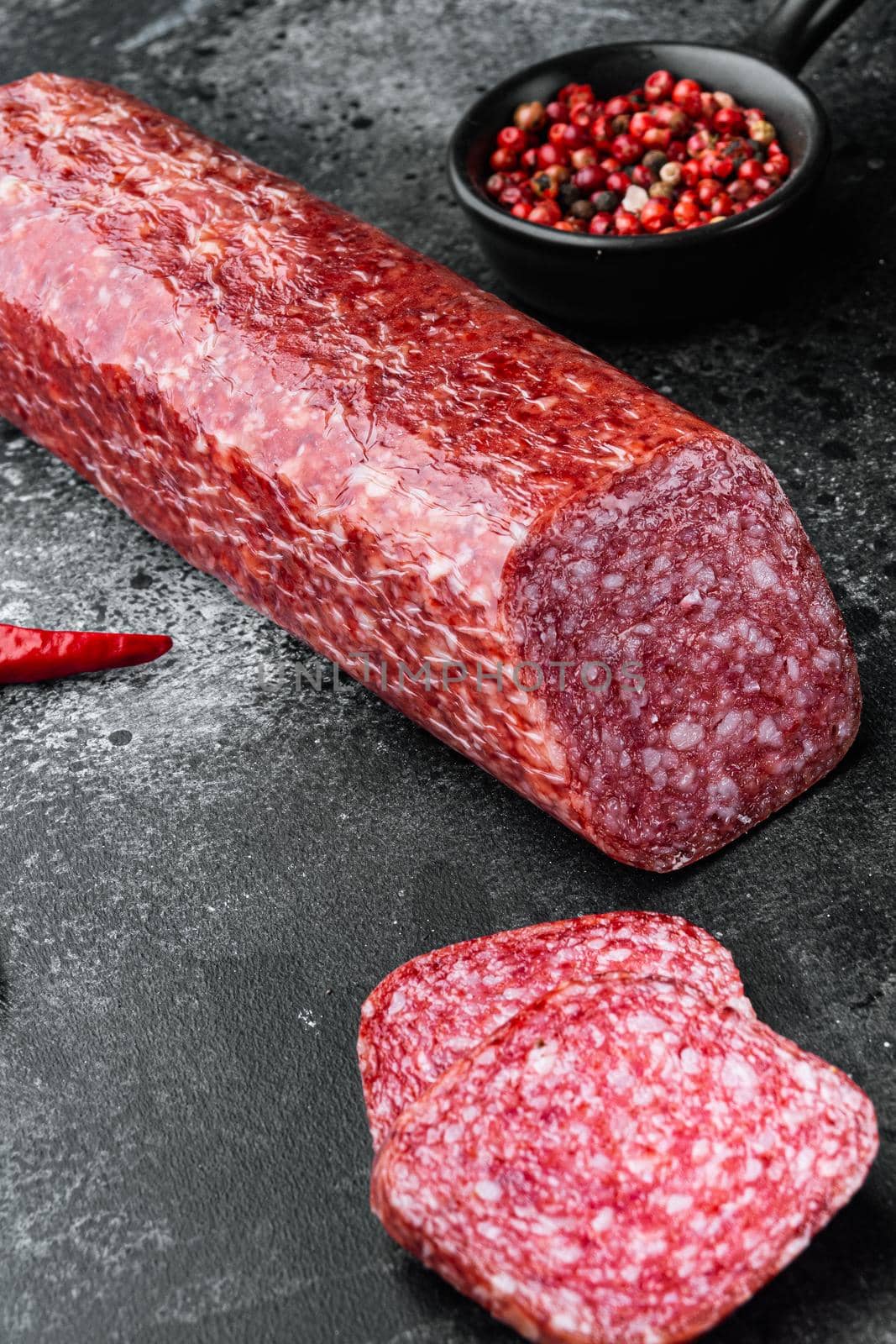 Dry salami sausage with fresh rosemary and spices set, on black dark stone table background