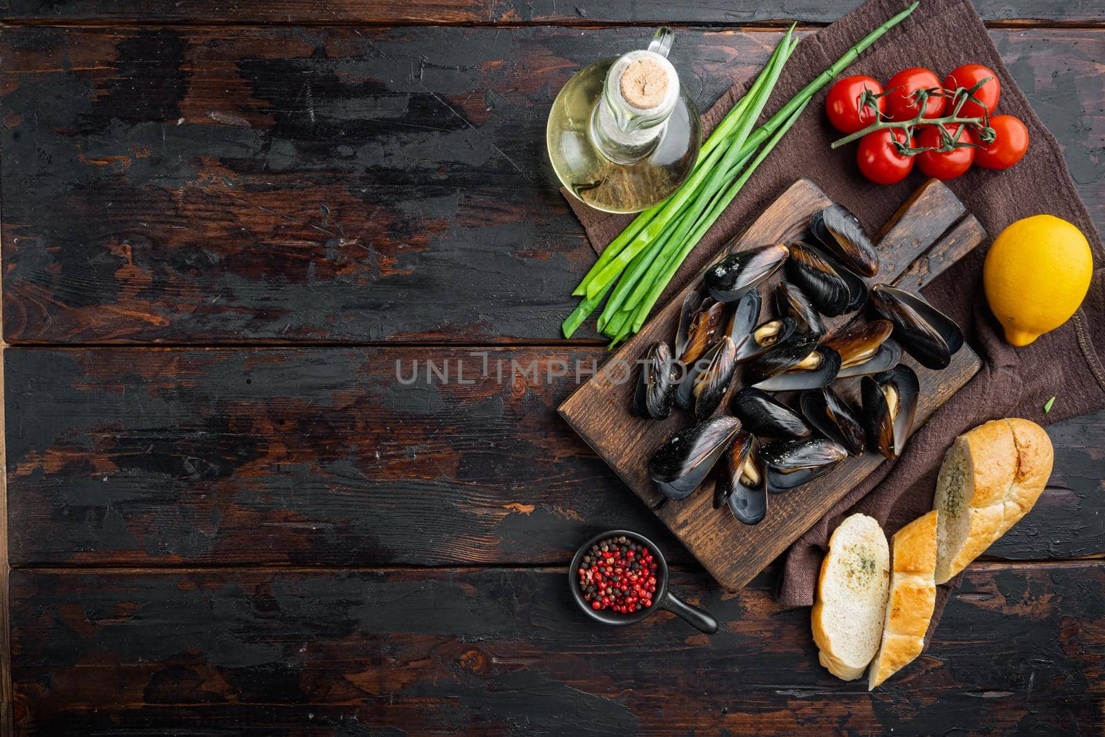 Steamed mussels in white wine set, on wooden cutting board, on old dark wooden table background, top view flat lay , with copyspace and space for text