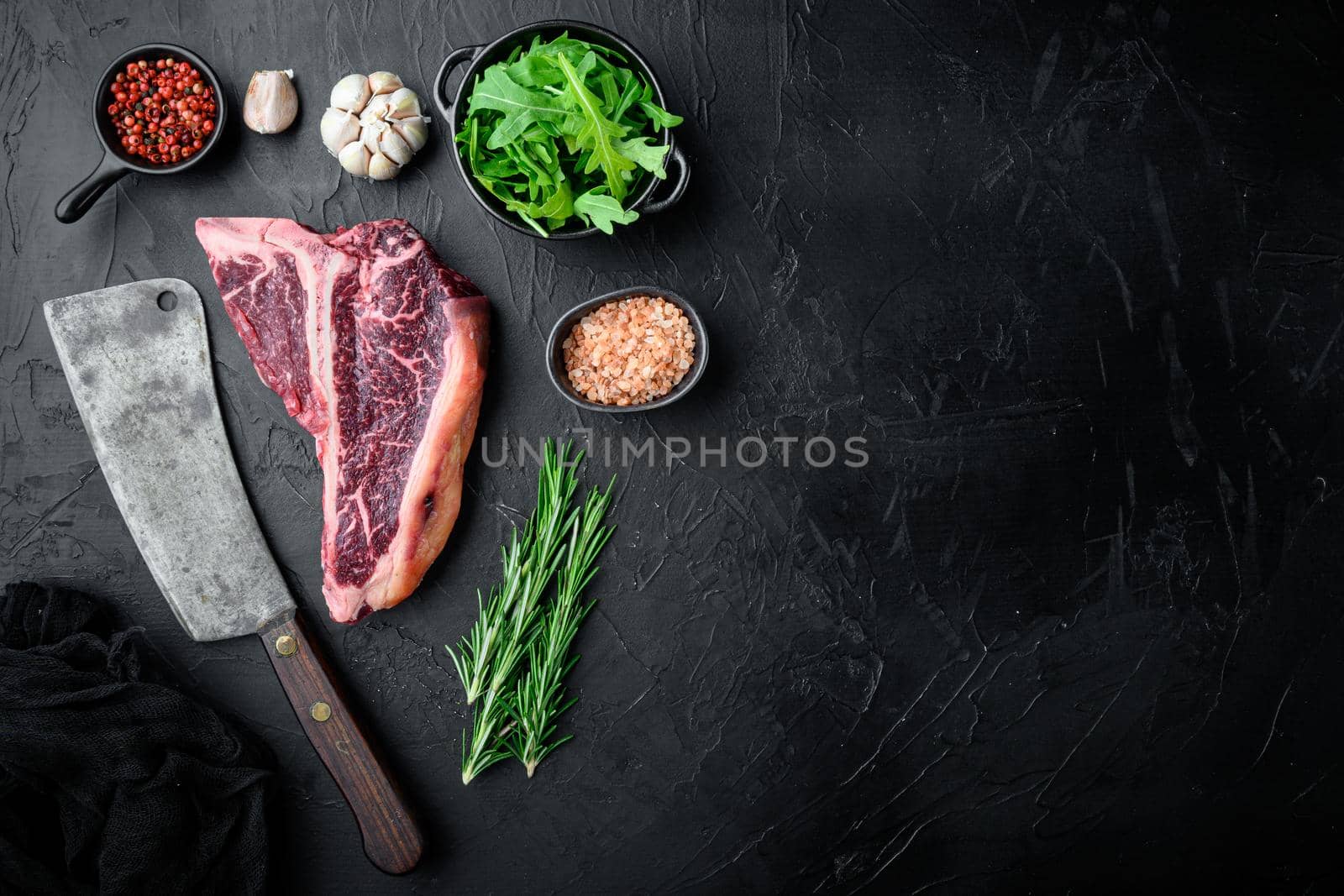 Thick Raw T-Bone Steak with Seasoning and Rosemary set, on black stone background, top view flat lay, with copy space for text