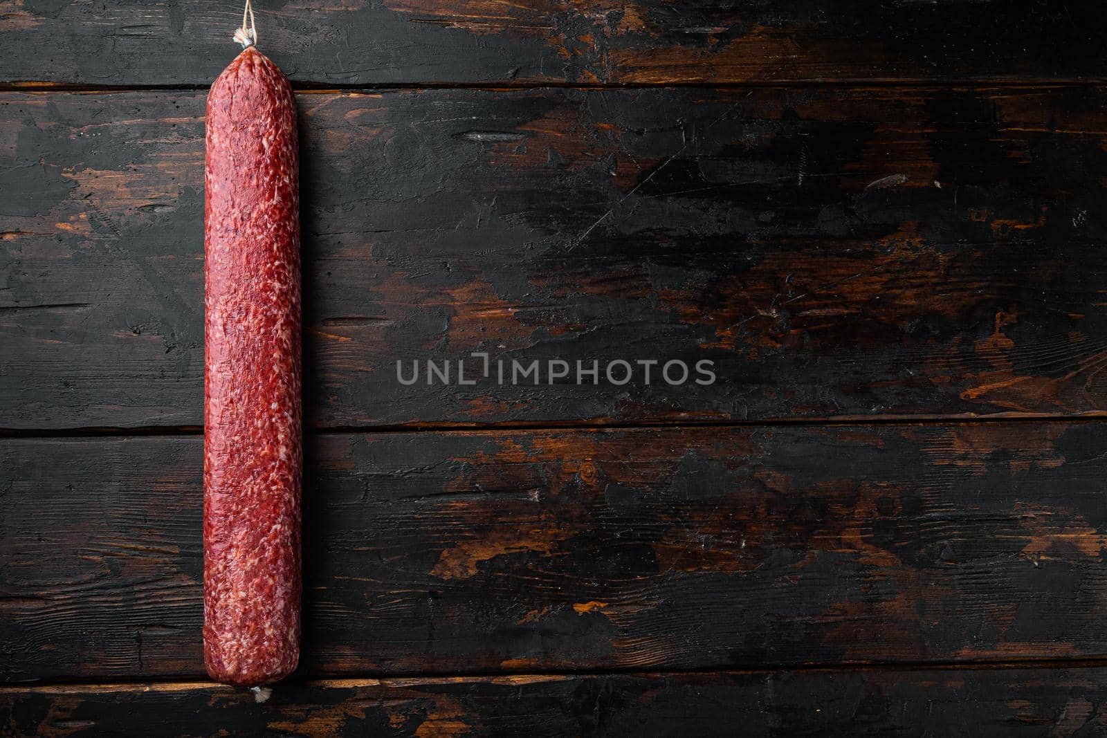 Traditional smoked salami sausage set, on old dark wooden table background, top view flat lay, with copy space for text