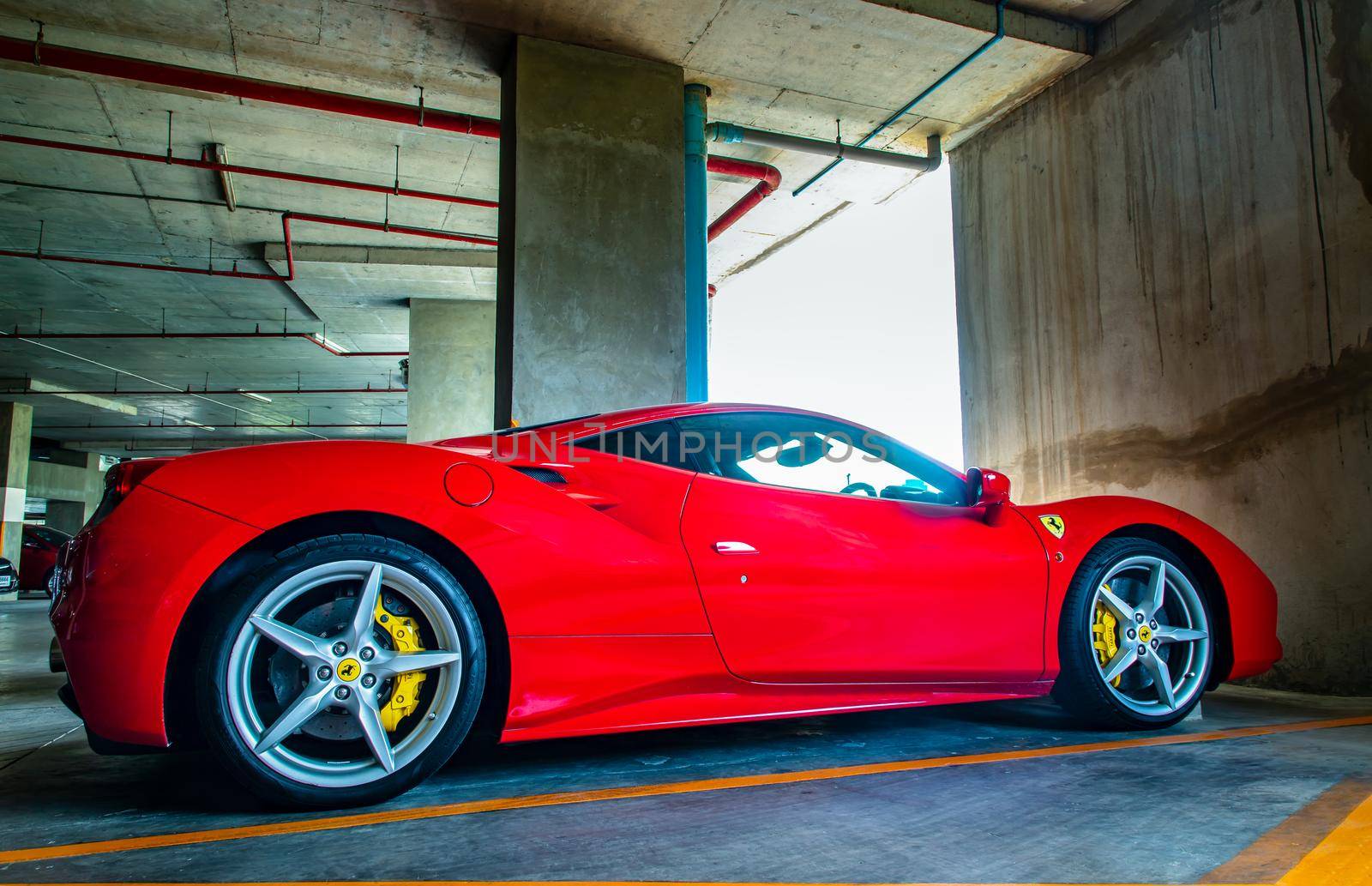 Bangkok, Thailand - 06 Jun 2021 : Side view of Red metallic Ferrari car in the parking lot. Ferrari is Italian sports car. Selective focus.