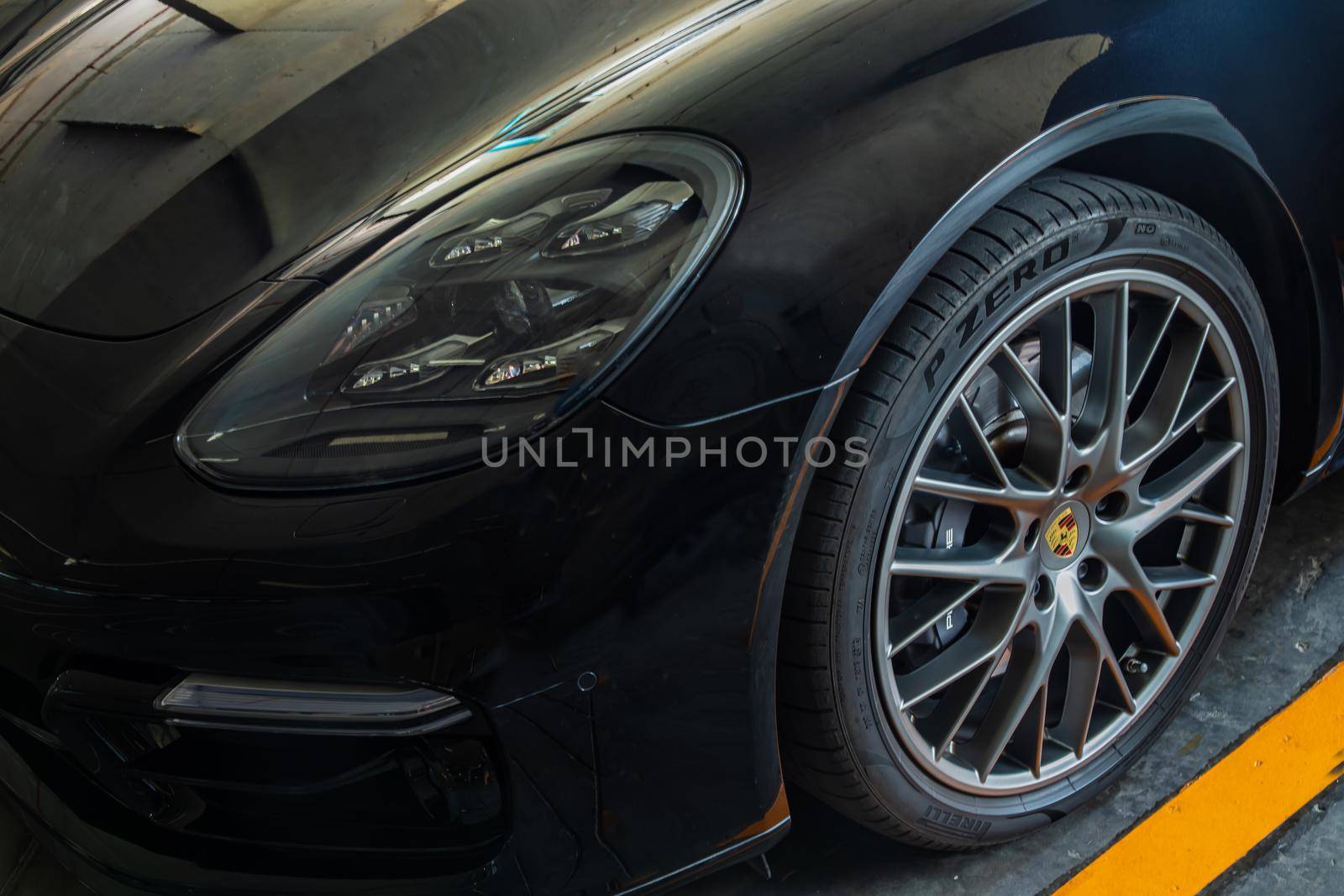 Close-up of Headlights, Wheel, and Rim of Black porsche sports car.  by tosirikul