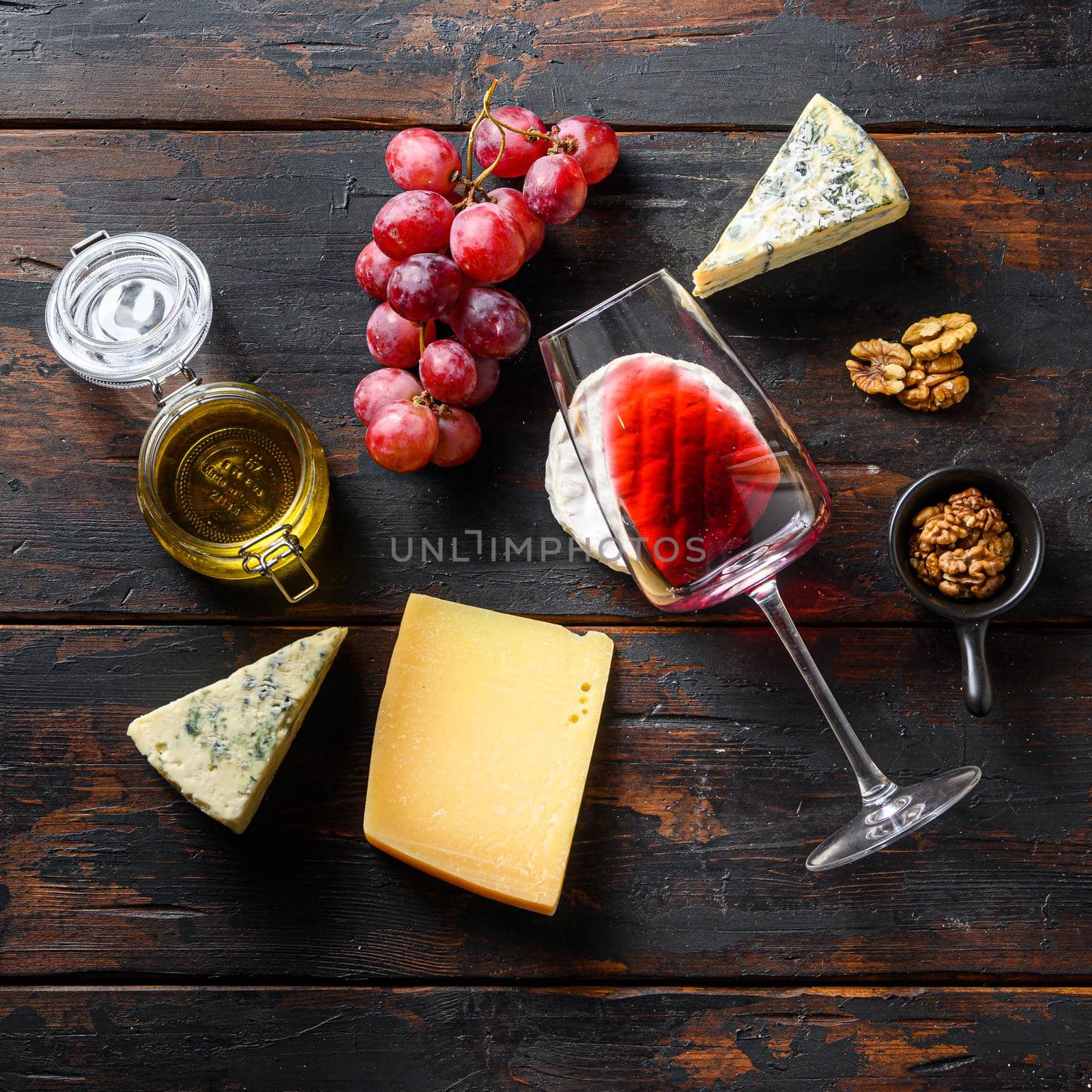 Fresh grapes , red wine, french cheeses, honey and nuts over rustic weathered wood. Top view with square crop by Ilianesolenyi