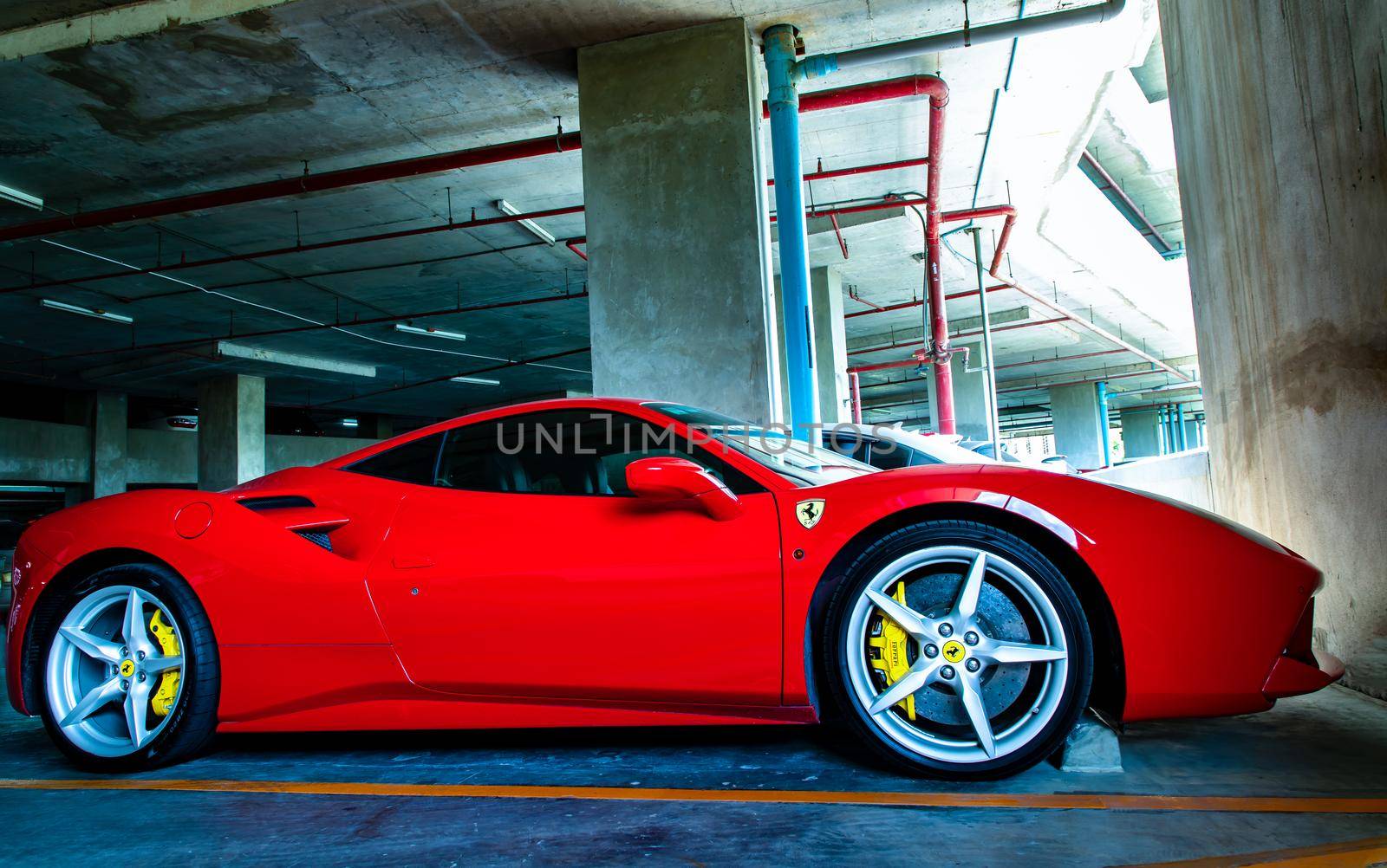 Side view of Red metallic Ferrari car in the parking lot. Ferrari is Italian sports car.  by tosirikul