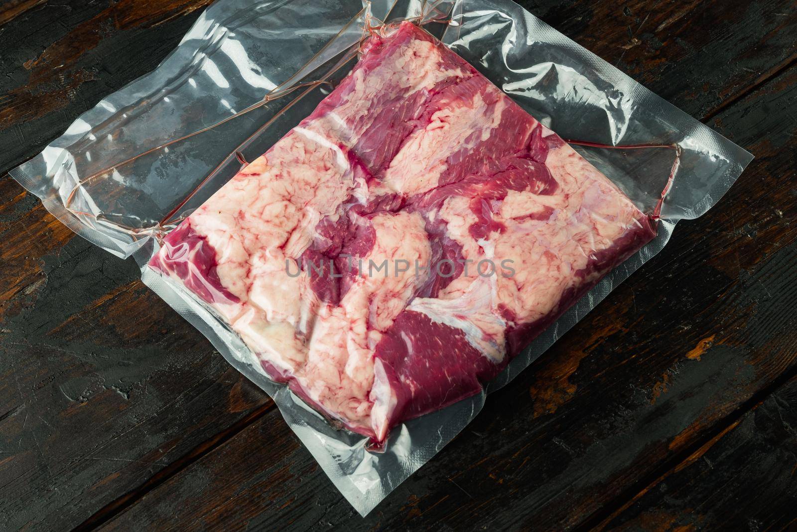Beef brisket vacuum packed set, on old dark wooden table background , with copyspace and space for text
