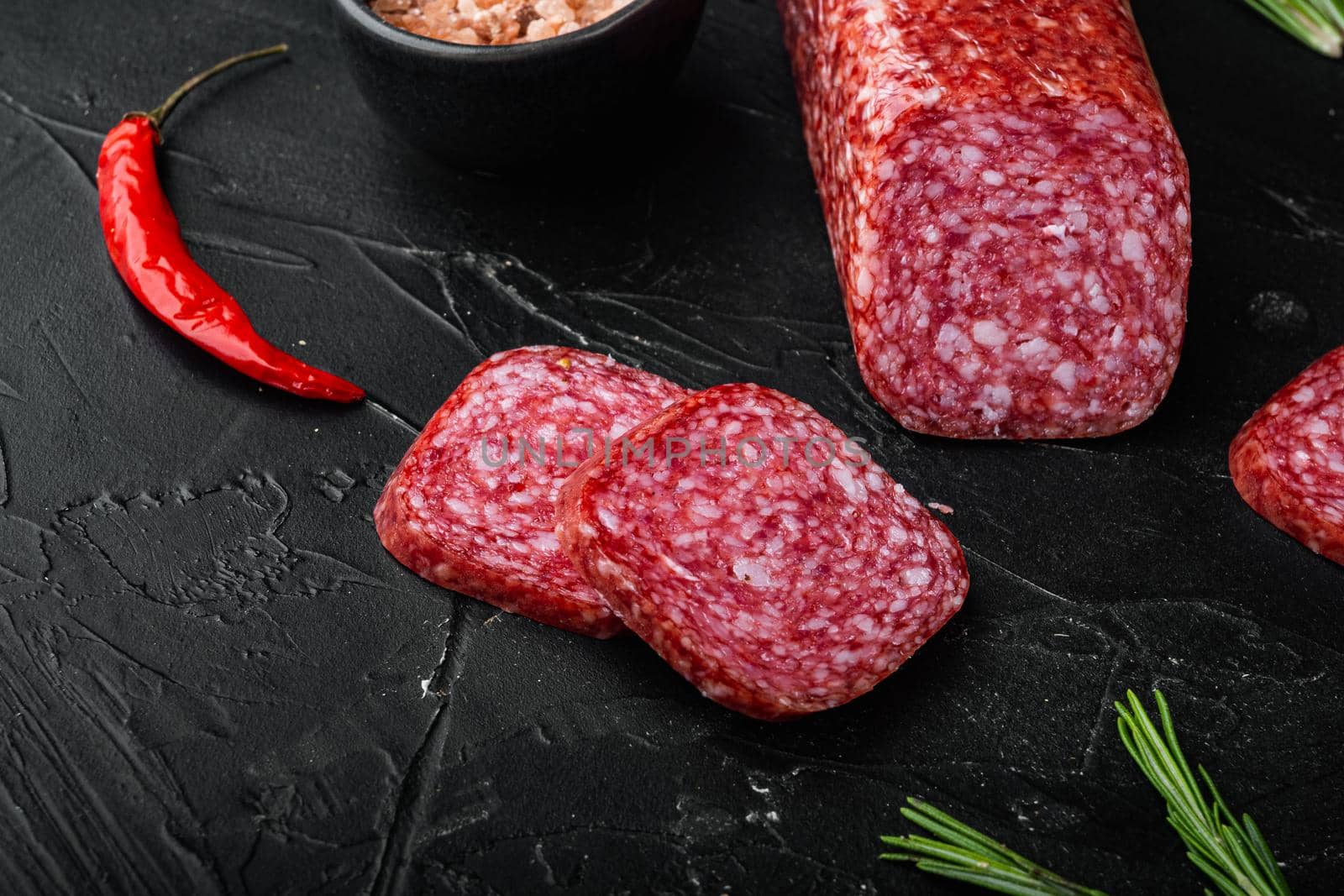 Salami, salami smoked sausage, sliced set, on black dark stone table background, with copy space for text
