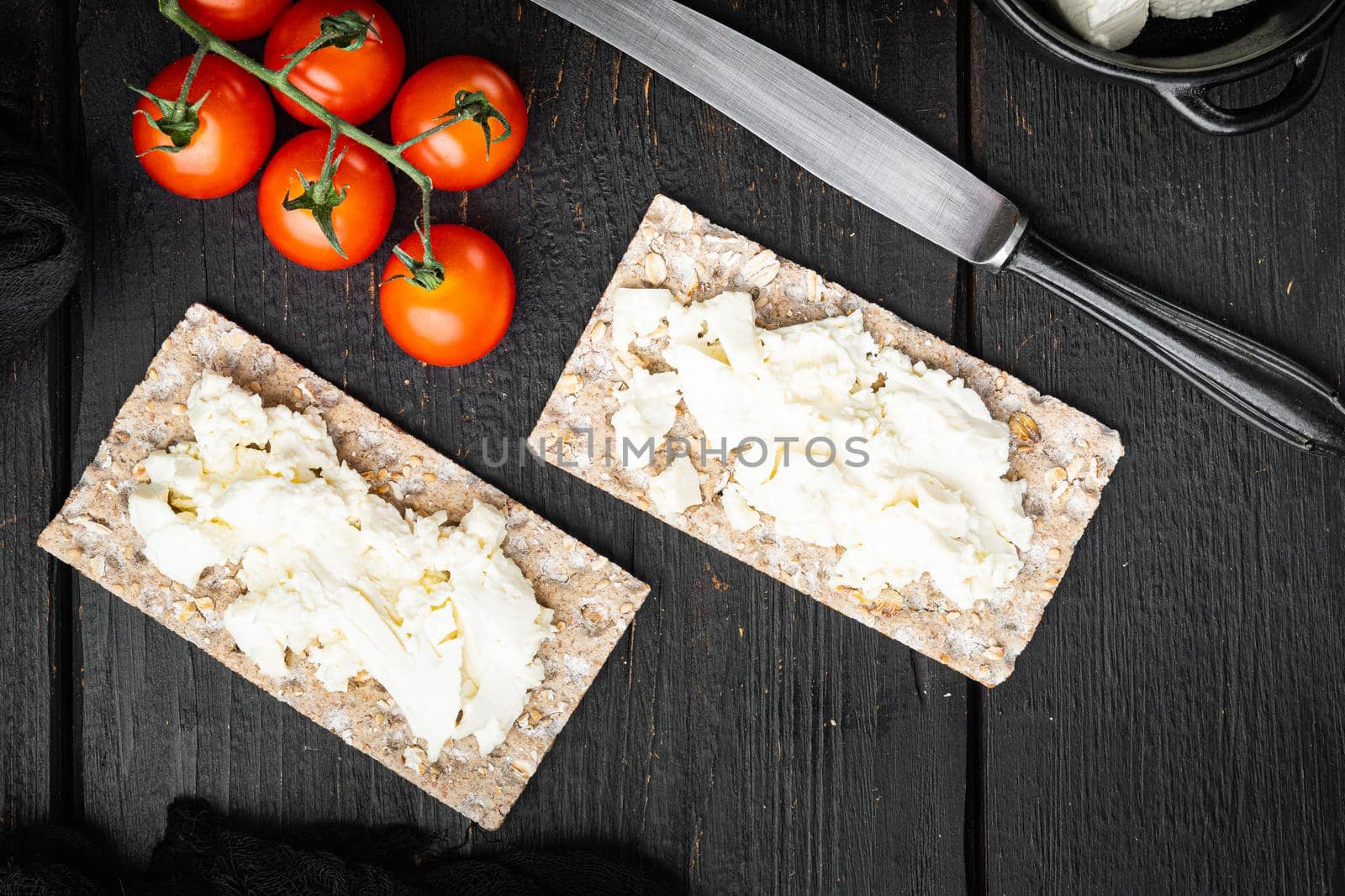 Wholegrain Rye Crispbread with cream cheese set, on black wooden table background, top view flat lay