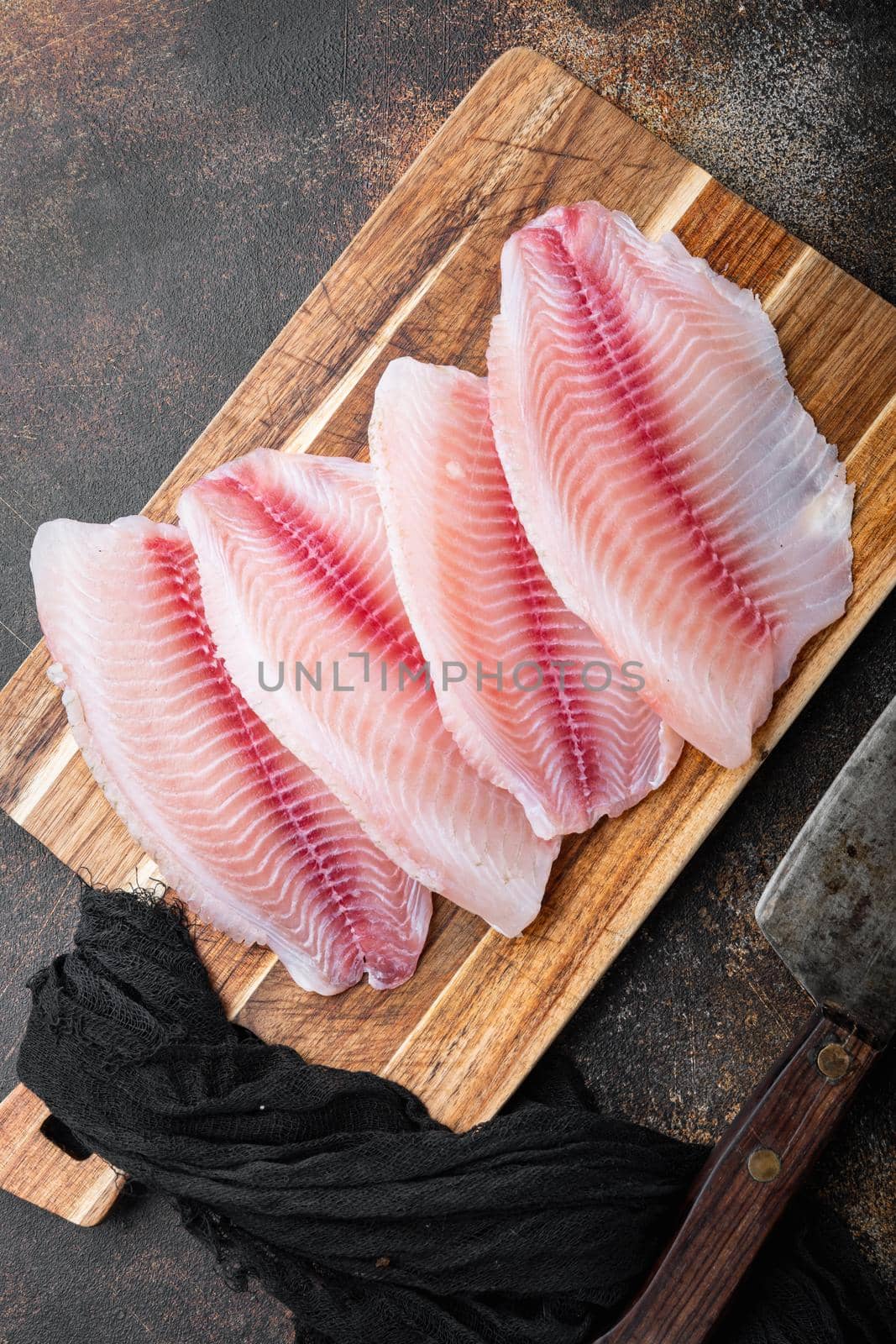 Tilapia fish, skinless meat, on old rustic background, top view