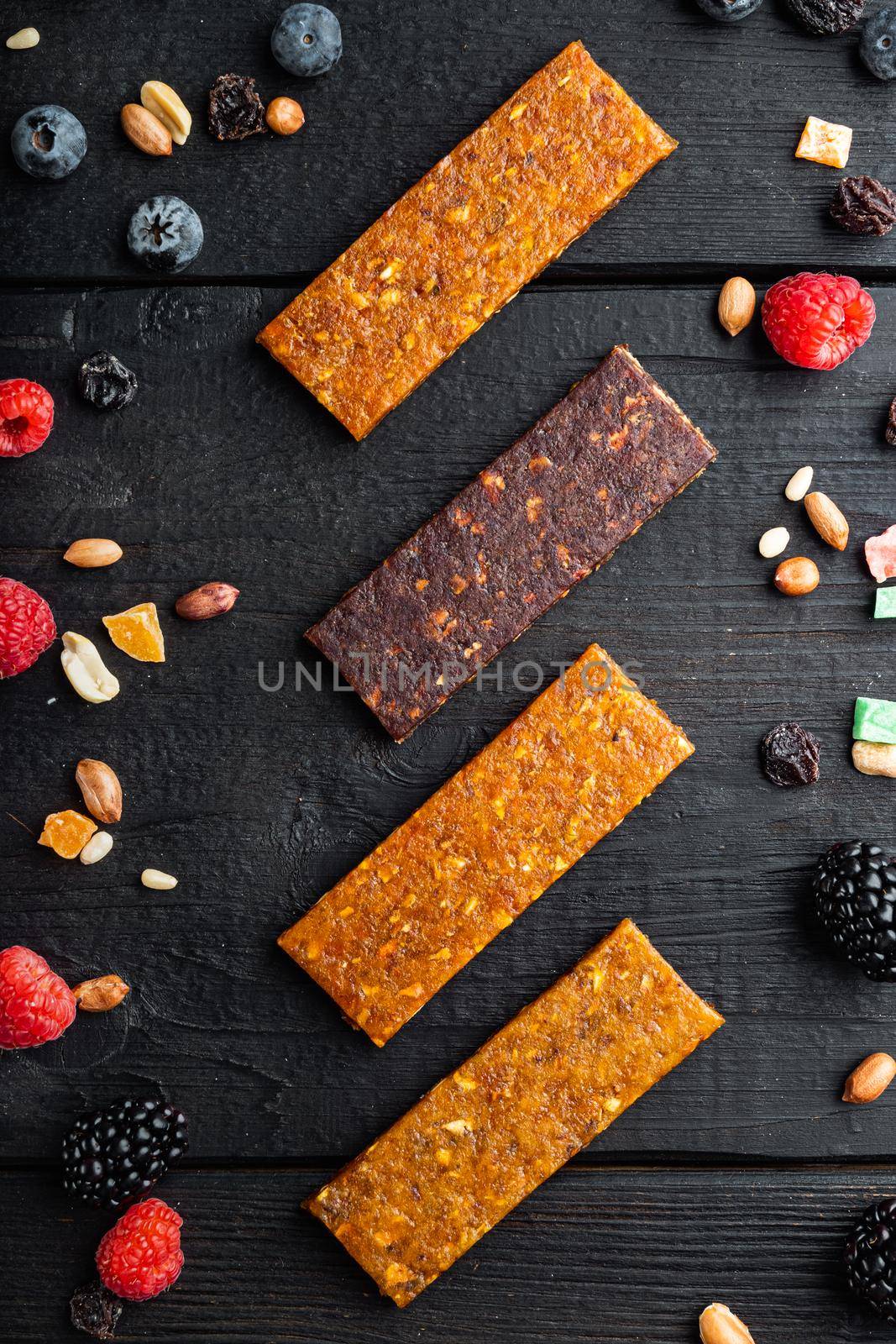 Healthy fitness energy bars with dried fruits and nuts, top view, on black wooden table
