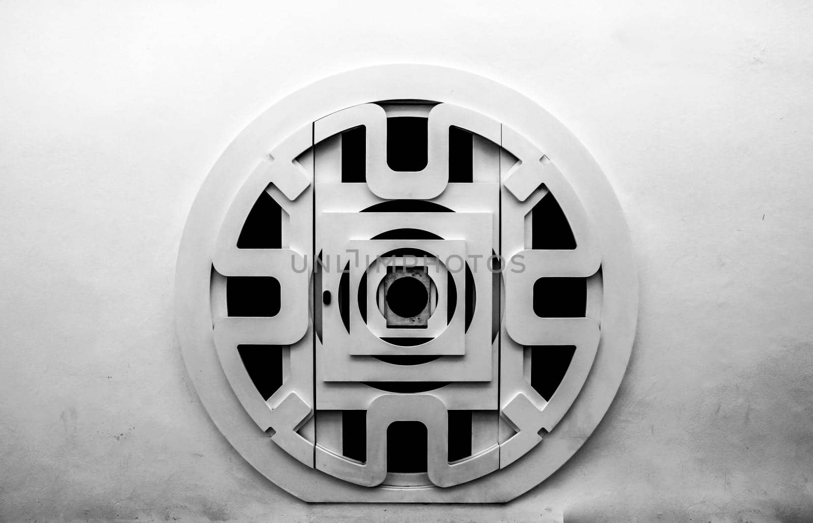 Circular wooden door with black iron details  and whitewashed facade in Altea, Alicante, Spain.
