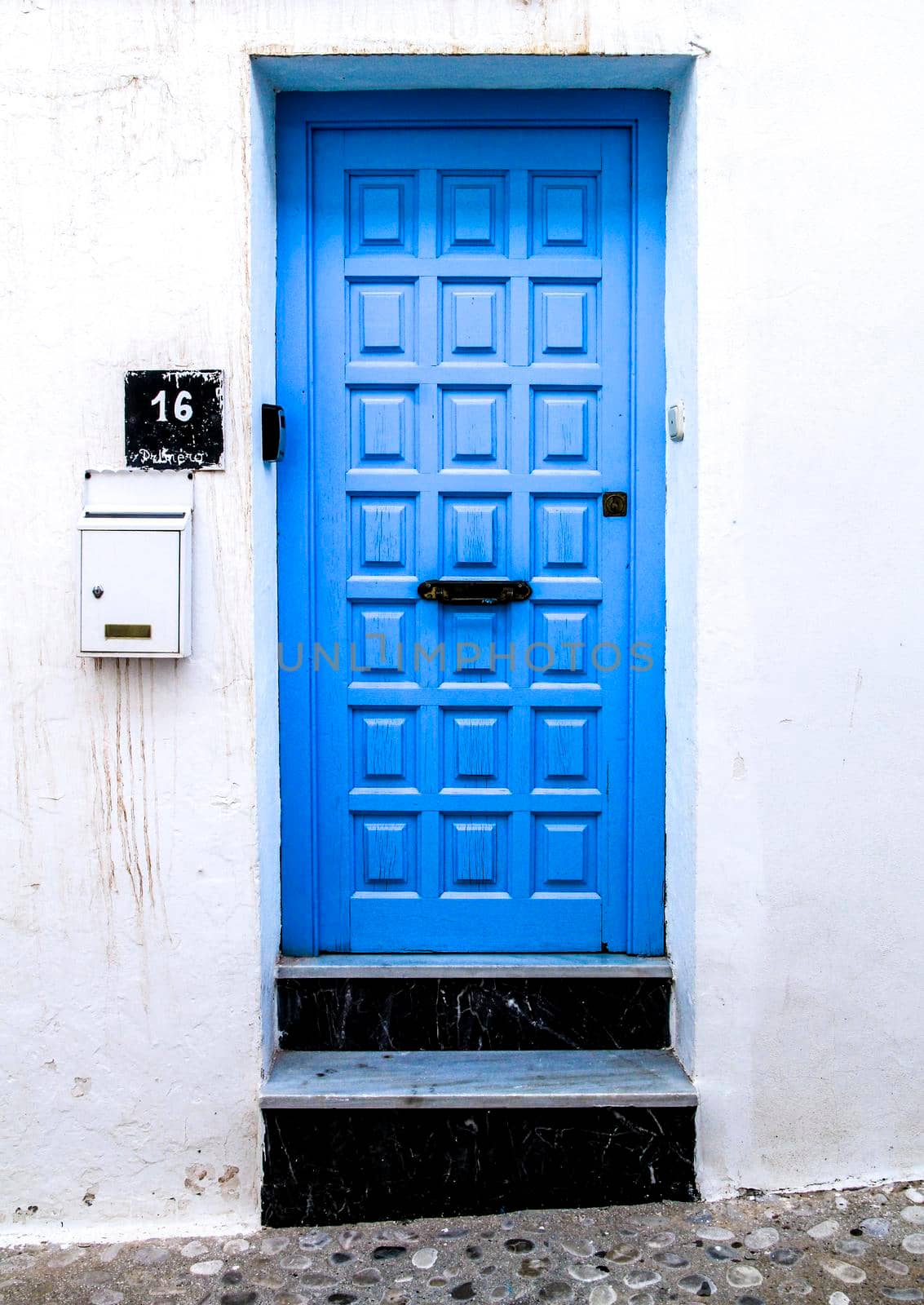 Blue wooden door with black iron details  and whitewashed facade in Altea, Alicante, Spain.